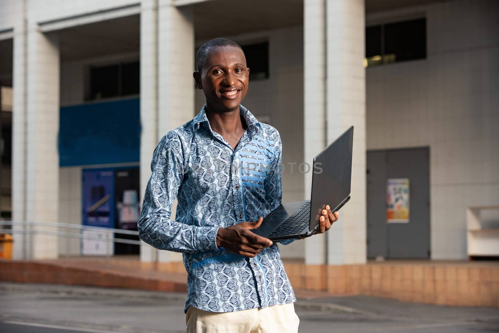 young african american man working standing up using a computer smiling in the street