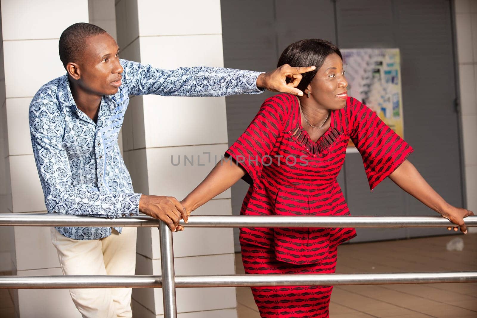 young businessman in traditional dress standing outside showing something to his partner.