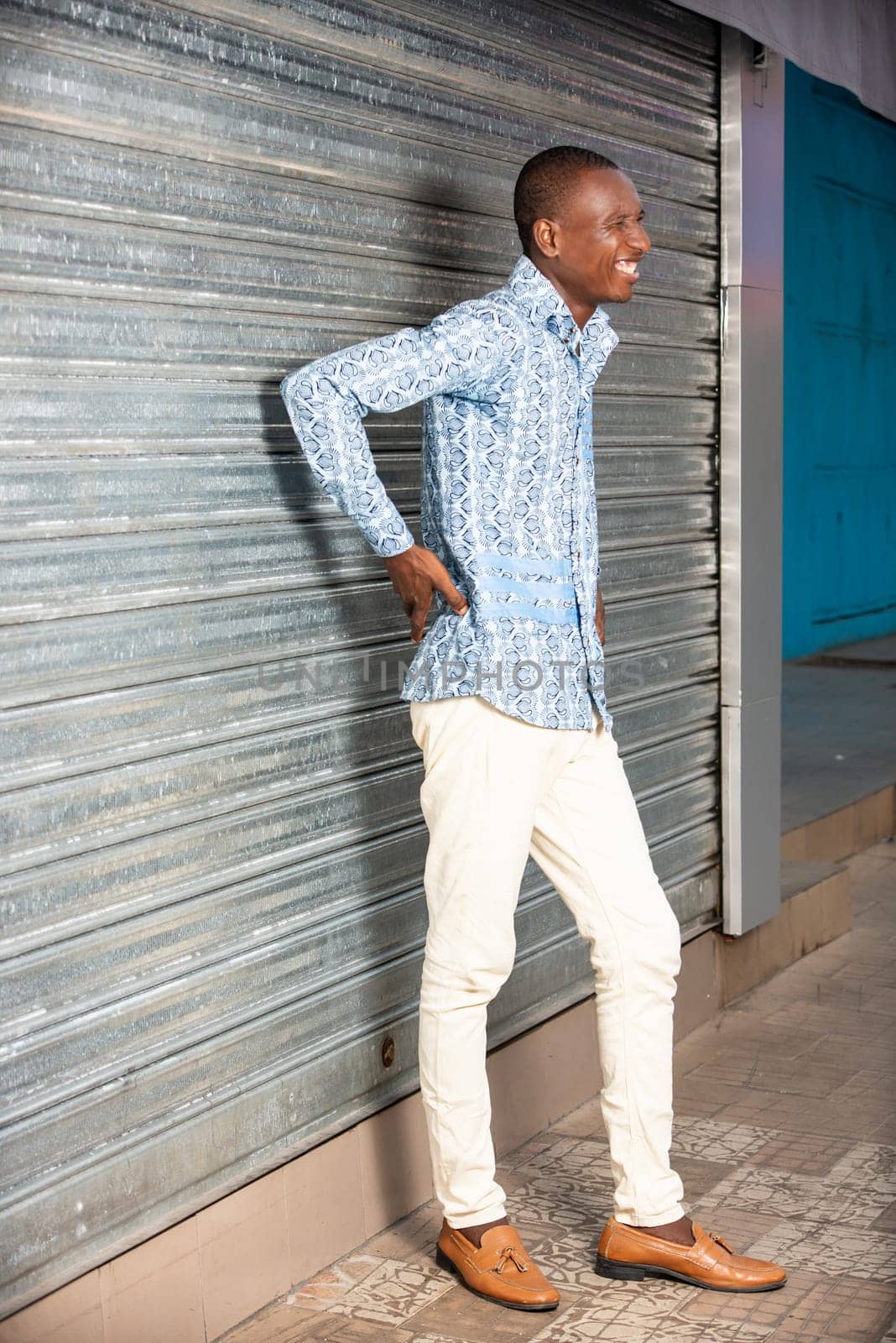 African adult man standing with back pain on the street