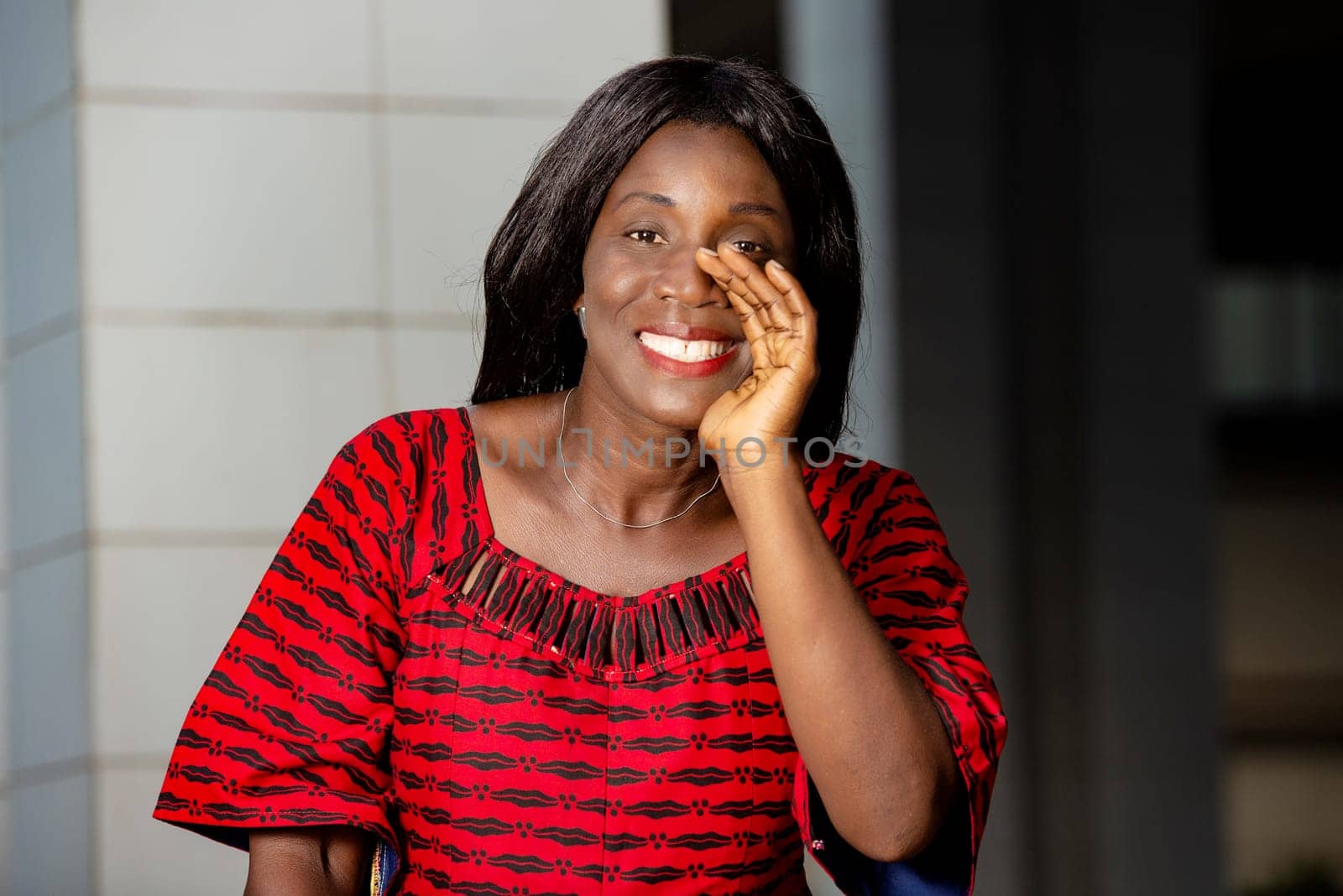 beautiful african woman standing in traditional outfit watching the camera smiling with gesture.