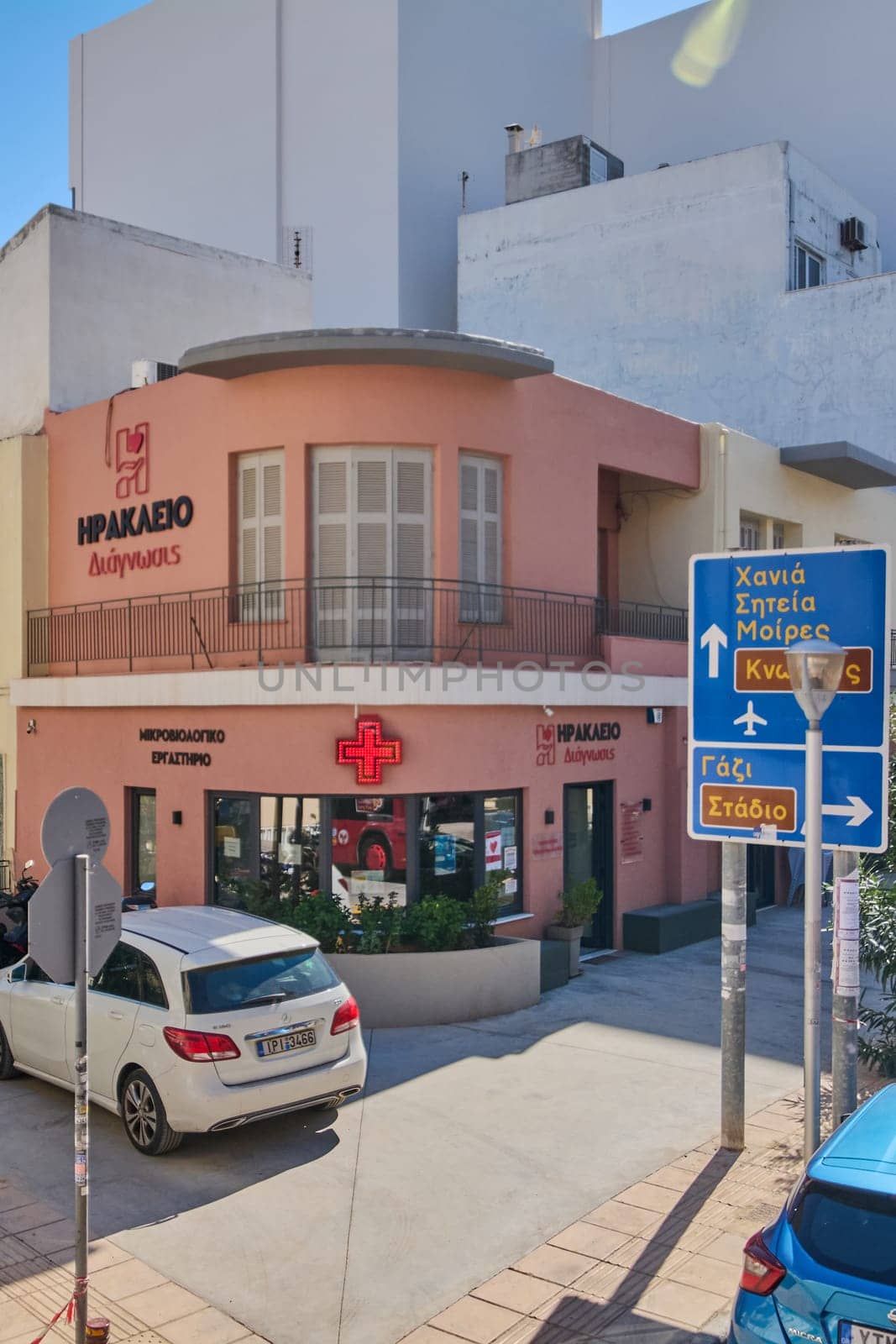 Crete.Greece - april 13, 2025: A Greek pharmacy with vibrant signage and architectural features that blend traditional elements with modern utility in Heraklion under sunny skies.