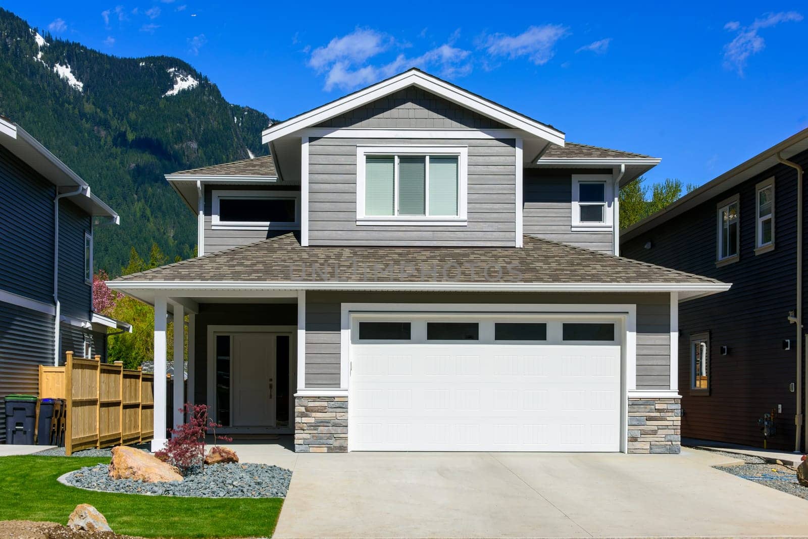 A perfect neighbourhood. Brand new house on the final stage of construction. Family house on snow mountain and blue sky background