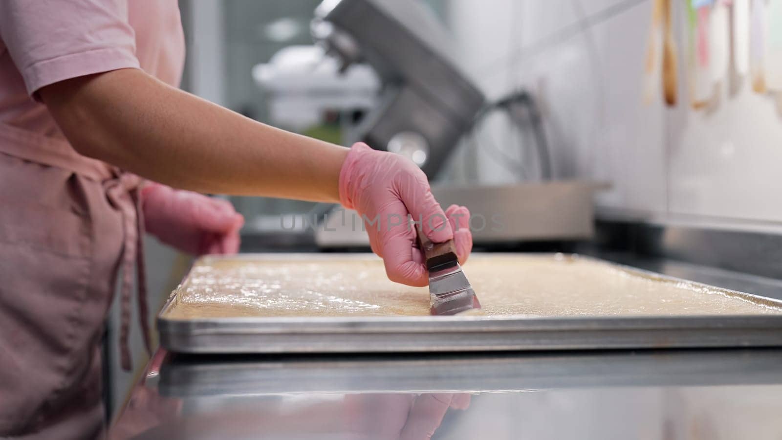 Confectioner woman working at kitchen. Spreading almond batter to smooth, silky texture. Delicate pastries - macarons, tarts, gluten-free bakes.