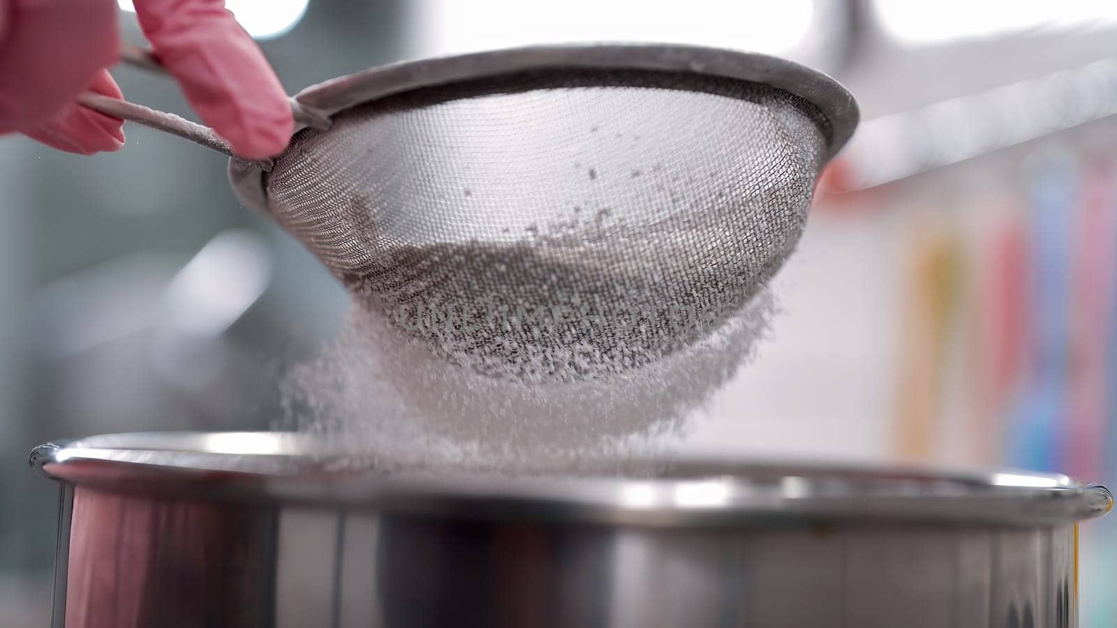 Making pastry, pizza dough or bread. Close-up slow motion of fine white flour falling through metal sieve. Powdery texture, home baking, cooking, kitchen preparation. High quality