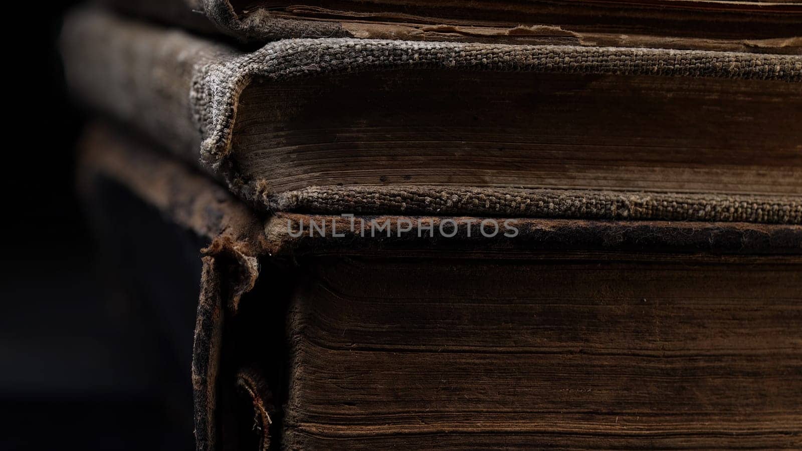 Close-up macro view of old book spines, revealing cracked leather, worn pages. Rich textures, faded bindings capture. History, antique literature. Nostalgia, knowledge, time concept. High quality