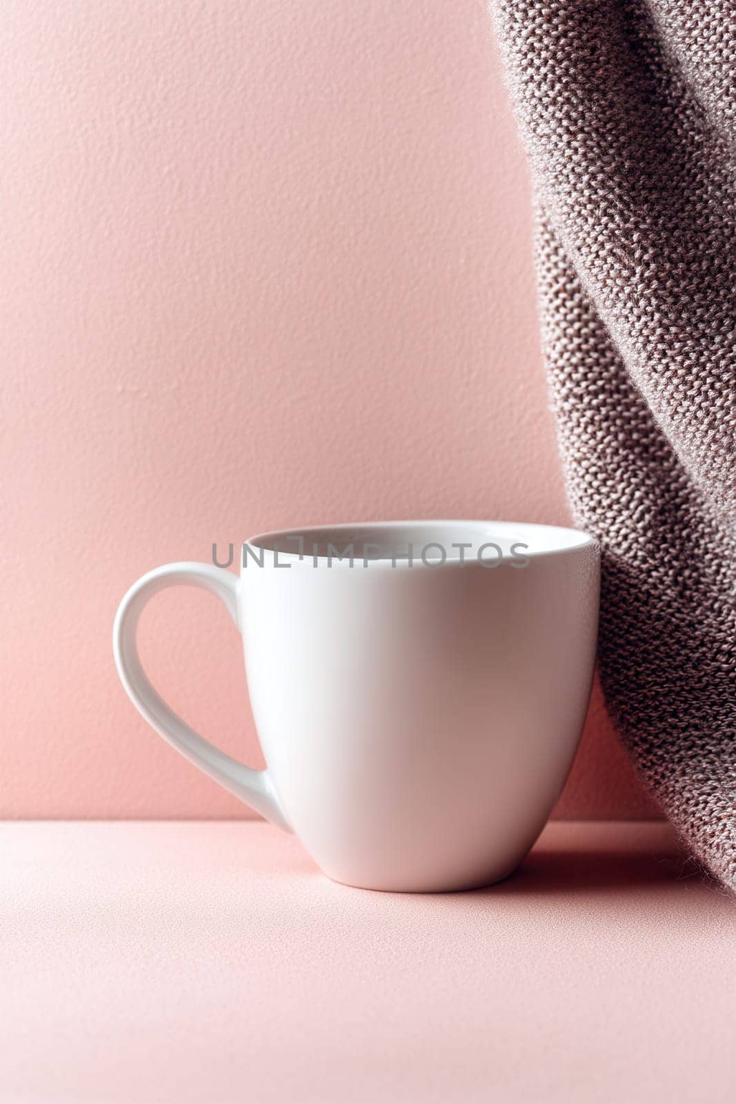 Minimal white ceramic mug on a pastel pink background beside soft knit fabric. Perfect for branding presentations, lifestyle content, warm beverage themes, and minimalist product mockups