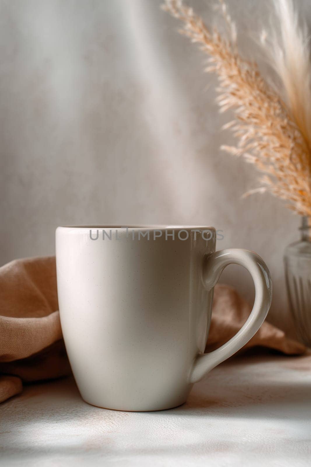 Cozy ceramic mug on soft fabric with dry grass in the background and natural sunlight. Great for calm lifestyle visuals, branding, product mockups, and morning coffee scenes