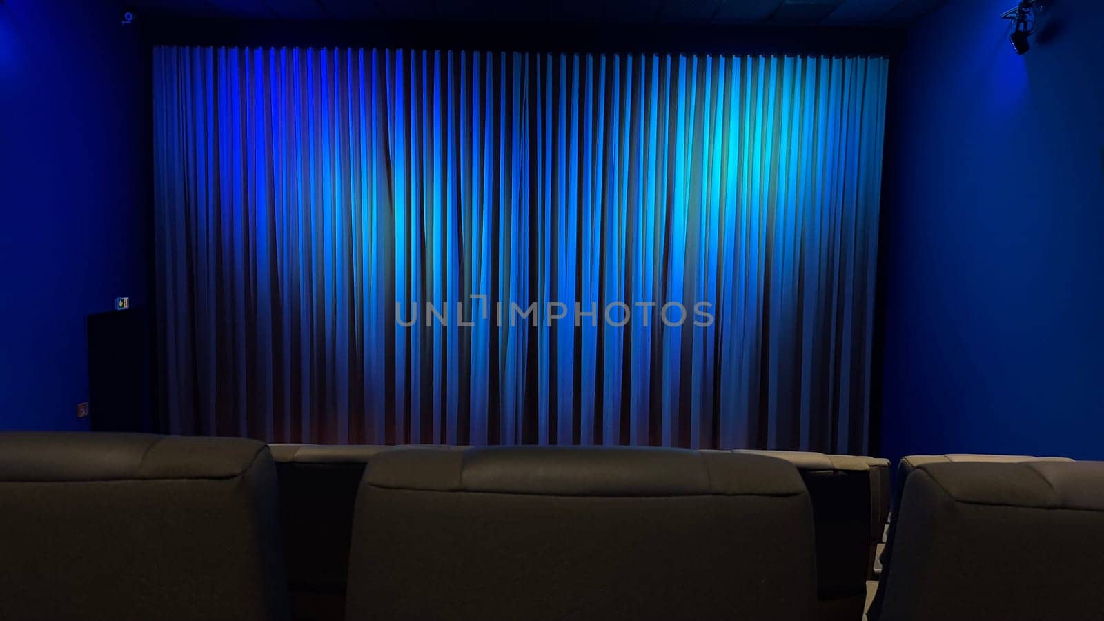 Empty Cinema Theater With Blue Curtains and Comfortable Seating. A serene theater interior showcasing blue curtains and modern seating, evoking a calm ambiance.