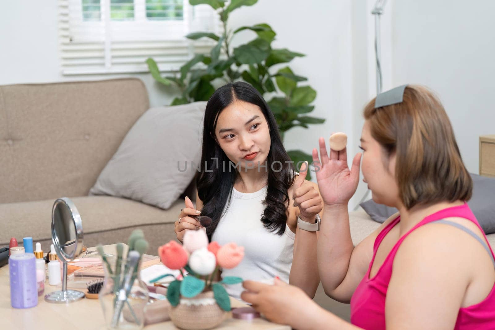 Friends bonding over a beauty session, as one applies makeup while the other learns about techniques, creating a joyful and supportive atmosphere.