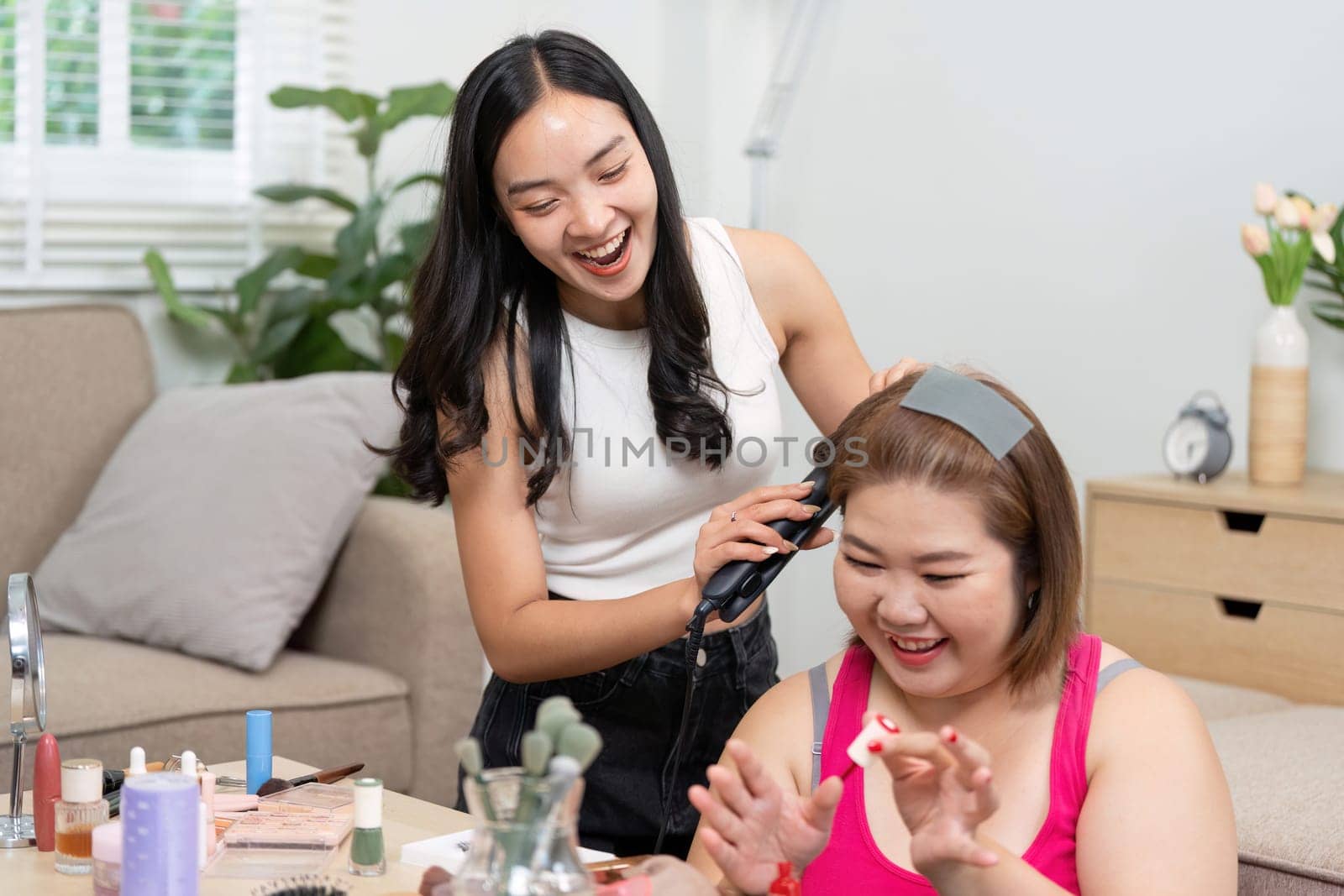 Two friends enjoy a beauty session at home, where one styles the other's hair, capturing the essence of fun, friendship, and self-care.