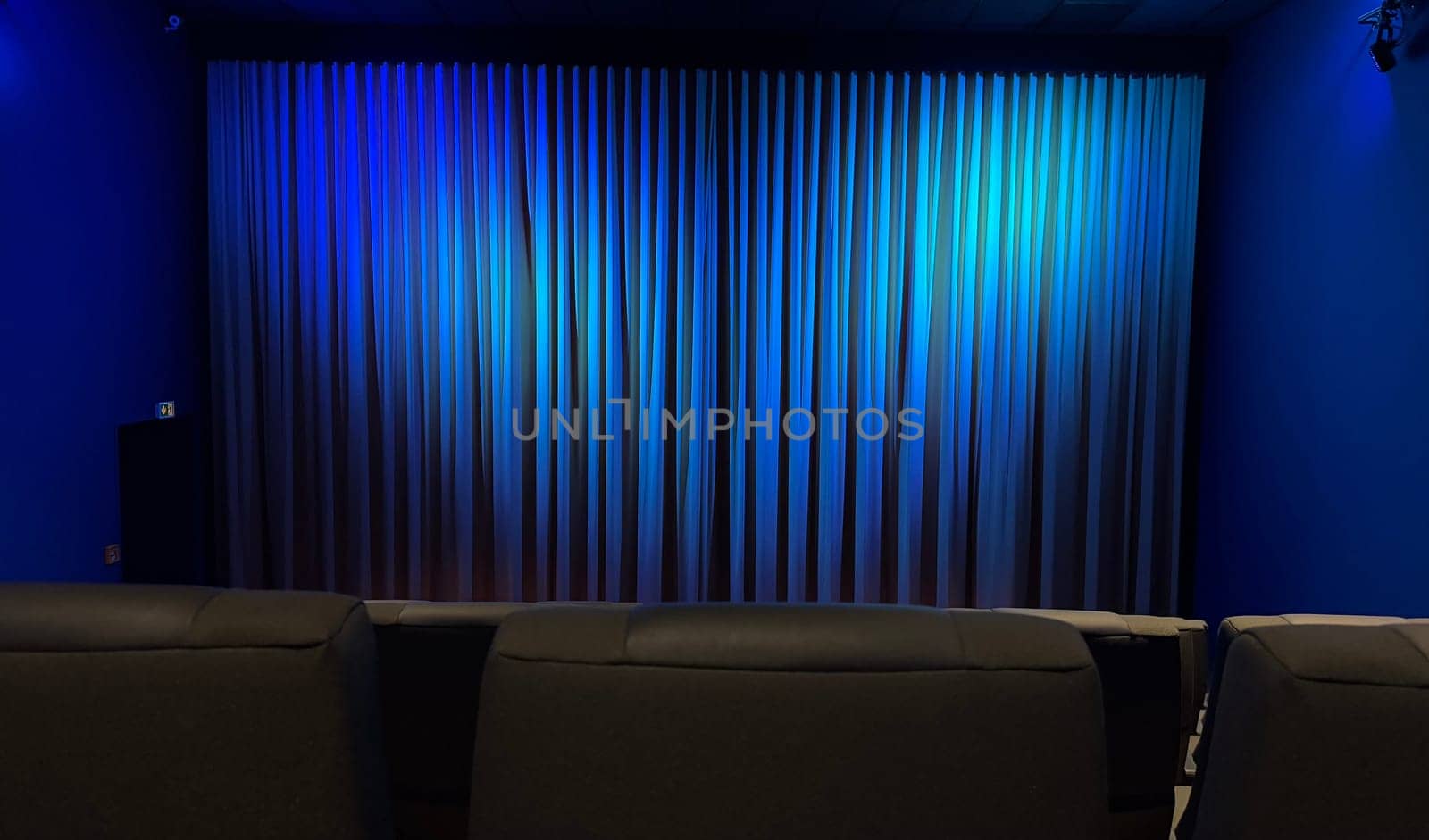 Empty Cinema Theater With Blue Curtains and Comfortable Seating. A serene theater interior showcasing blue curtains and modern seating, evoking a calm ambiance.