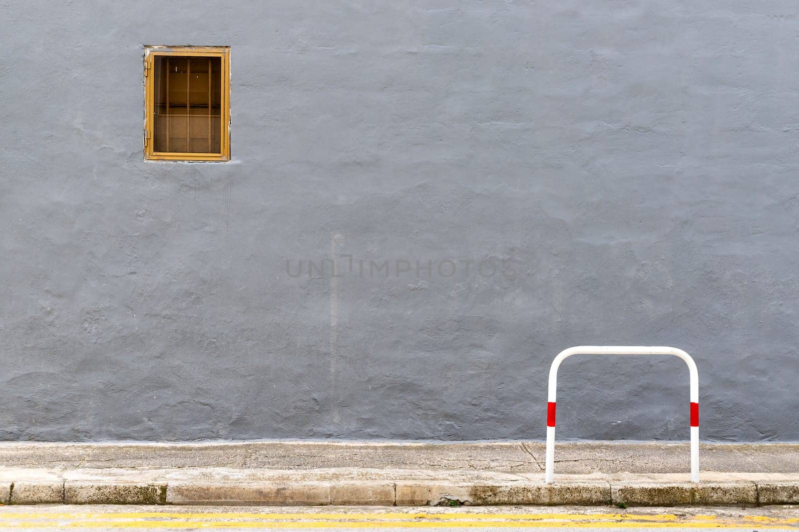 A dark gray wall with a small window in a metal frame, minimalist composition
