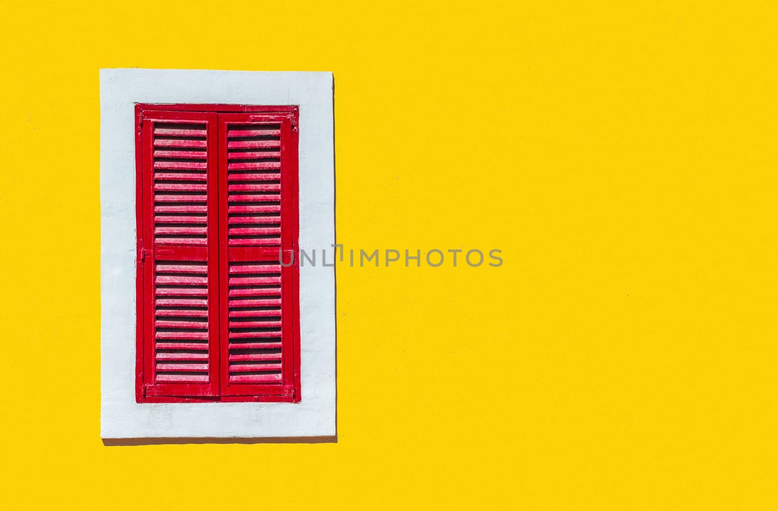 Minimalist style photo of yellow wall with red window in white frame, Murano, Venice, Italy
