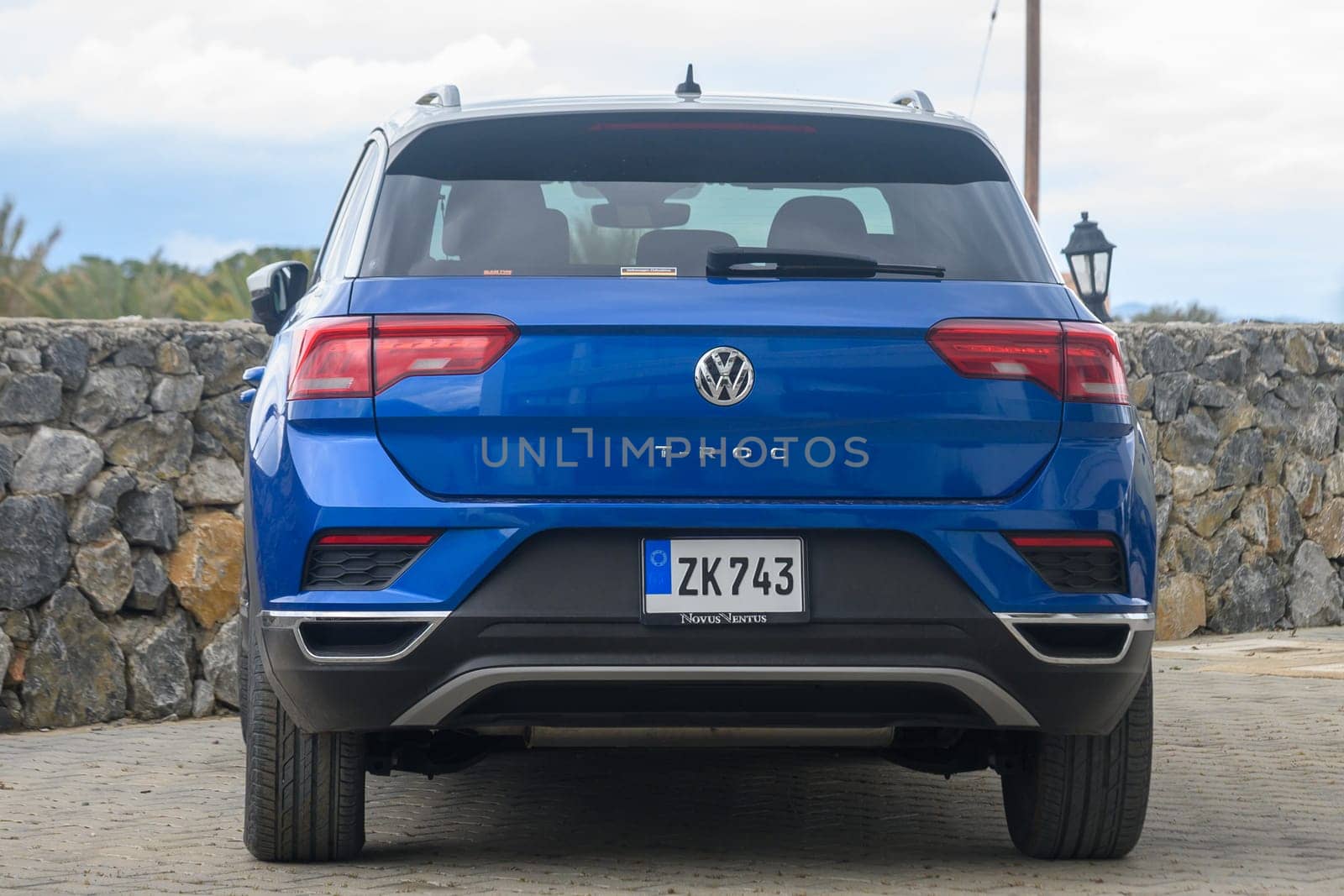 Gaziveren Cyprus -10.04.2025 A vibrant blue SUV stands proudly by a sturdy stone wall, showcasing its modern design against a backdrop of soft clouds. The quiet surroundings enhance its striking appearance.