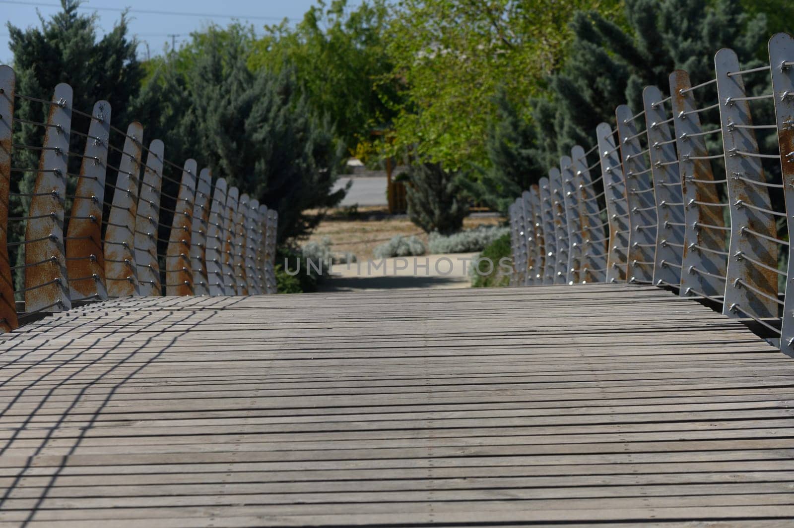 A graceful bridge stretches across a calm pathway in a peaceful park, surrounded by lush greenery and inviting visitors to wander and enjoy the tranquility of nature.
