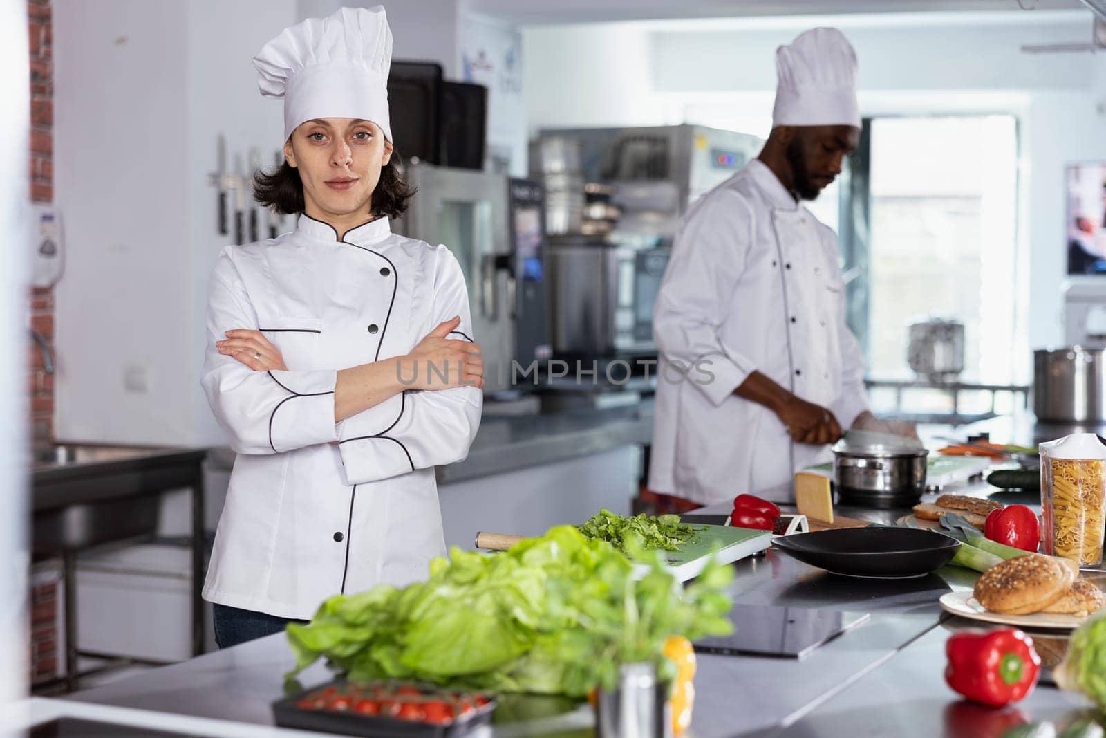 In a luxurious restaurant kitchen, female chef cooking tasty fine dining meals by preparing ingredients using stainless steel tools at the kitchen counter. Mastering food prep techniques.