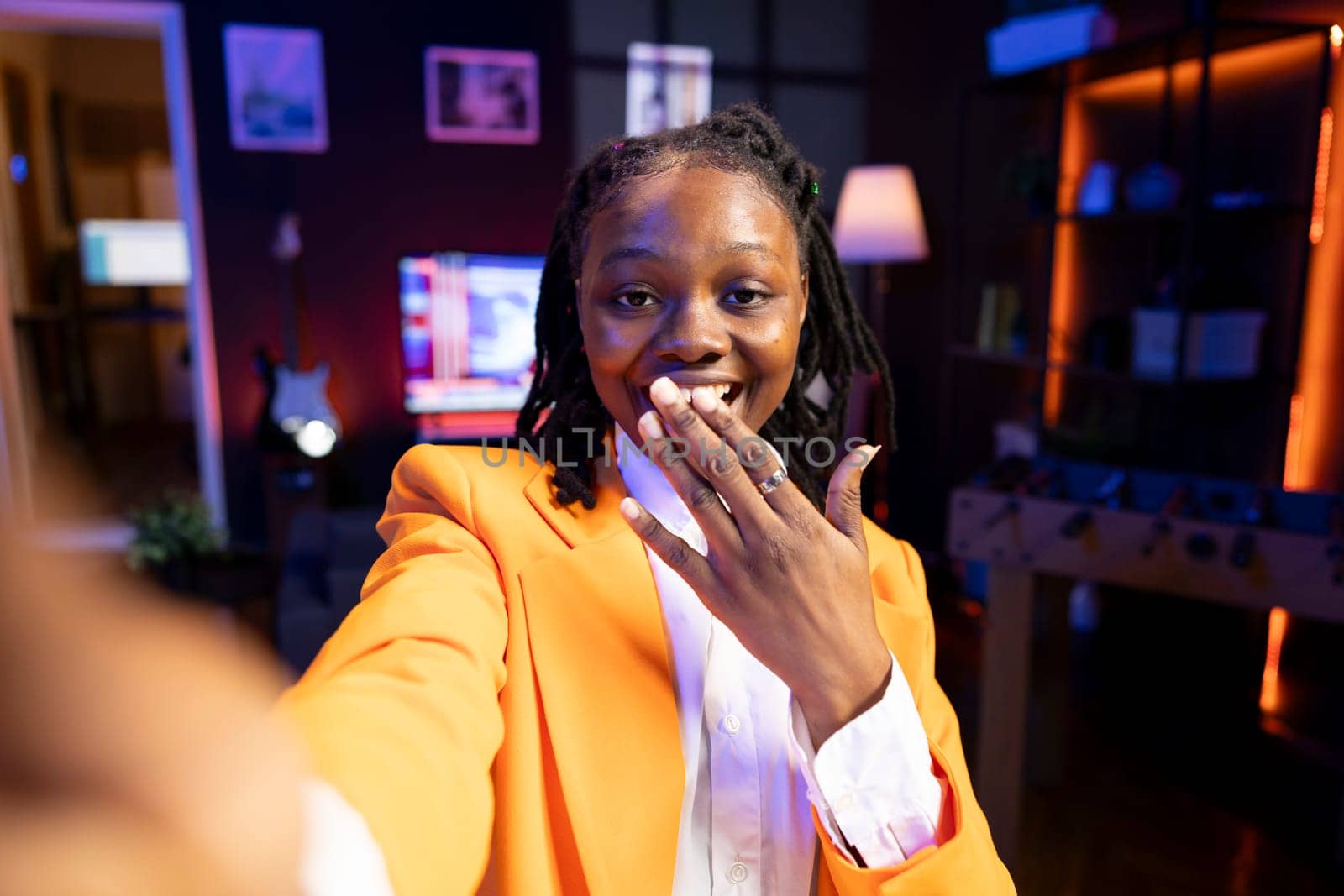 Cheerful girl excited to film in living room used as professional studio for recording vlogs for online channel. Happy teenager in apartment delighted to discuss topics with fans