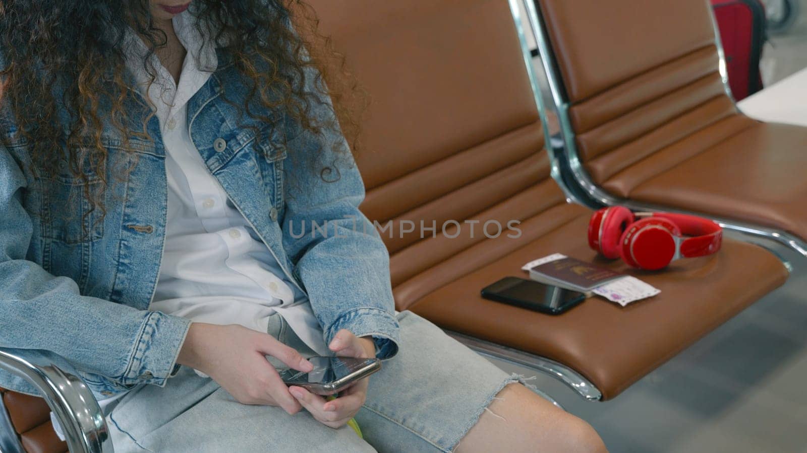 Passenger traveler woman in airport gate play smartphone for waiting air vacation travel, hipster female sitting and using mobile phone in terminal hall area while waiting for her traveling flight