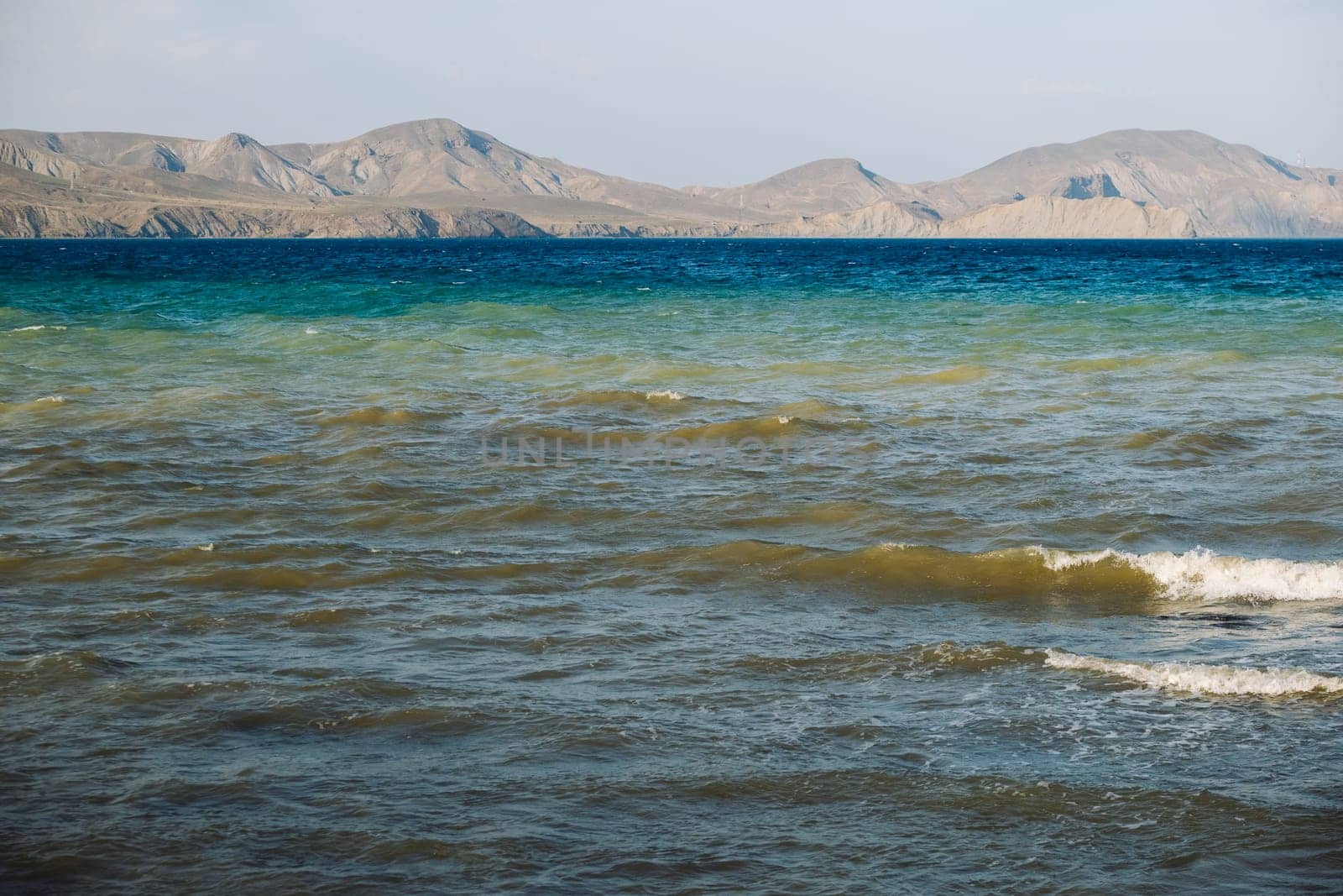 Waves gently lapping the shore in Crimea with mountains in the background