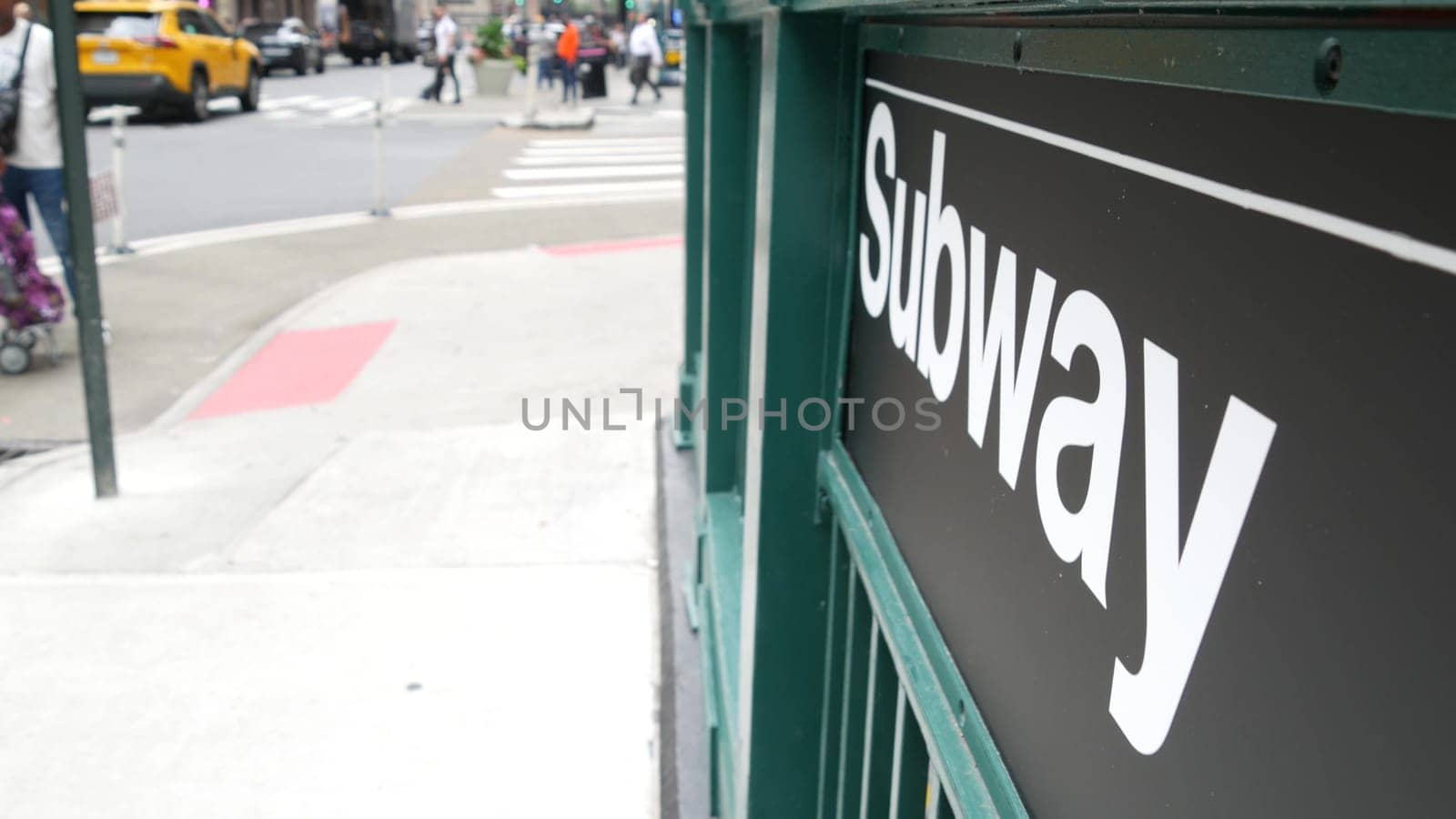 New York City, United States - 29 Aug 2023: Subway sign, underground metro station. Metropolitan entrance fence, public passenger transport exit, yellow taxi cab. Pedestrians people, Manhattan street.