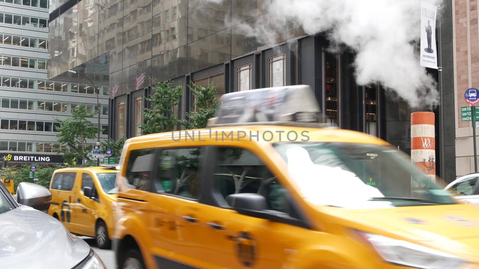 New York City, United States - 11 Sept 2023: Manhattan Midtown street, 5 Fifth 5th avenue. American urban road car traffic, Yellow taxi in USA. Hot smoke stack, orange steam pipe. Rolex store.