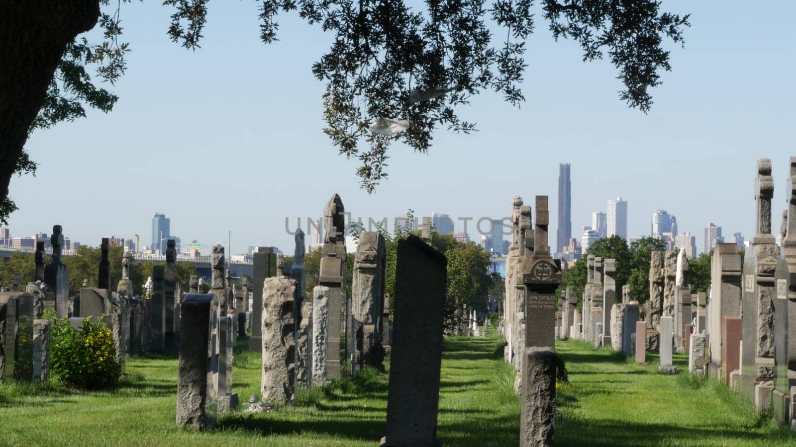 New York City, United States - 14 Sept 2023: Calvary cemetery in Queens, USA. Manhattan Downtown urban skyline cityscape architecture. Tombstones on graves, huge graveyard. Large cemetry grass lawn.