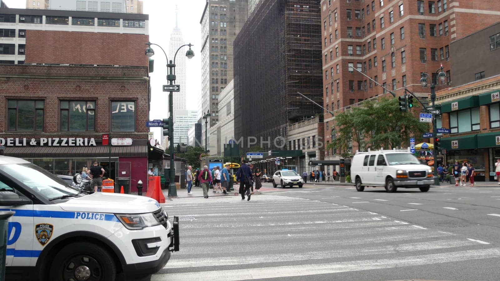 New York City, United States - 29 Aug 2023: Police patrol car, USA NYPD 911, Manhattan Midtown 34th street. American cop auto, 9 avenue. Urban road traffic. People, Empire State Building, New Yorker.