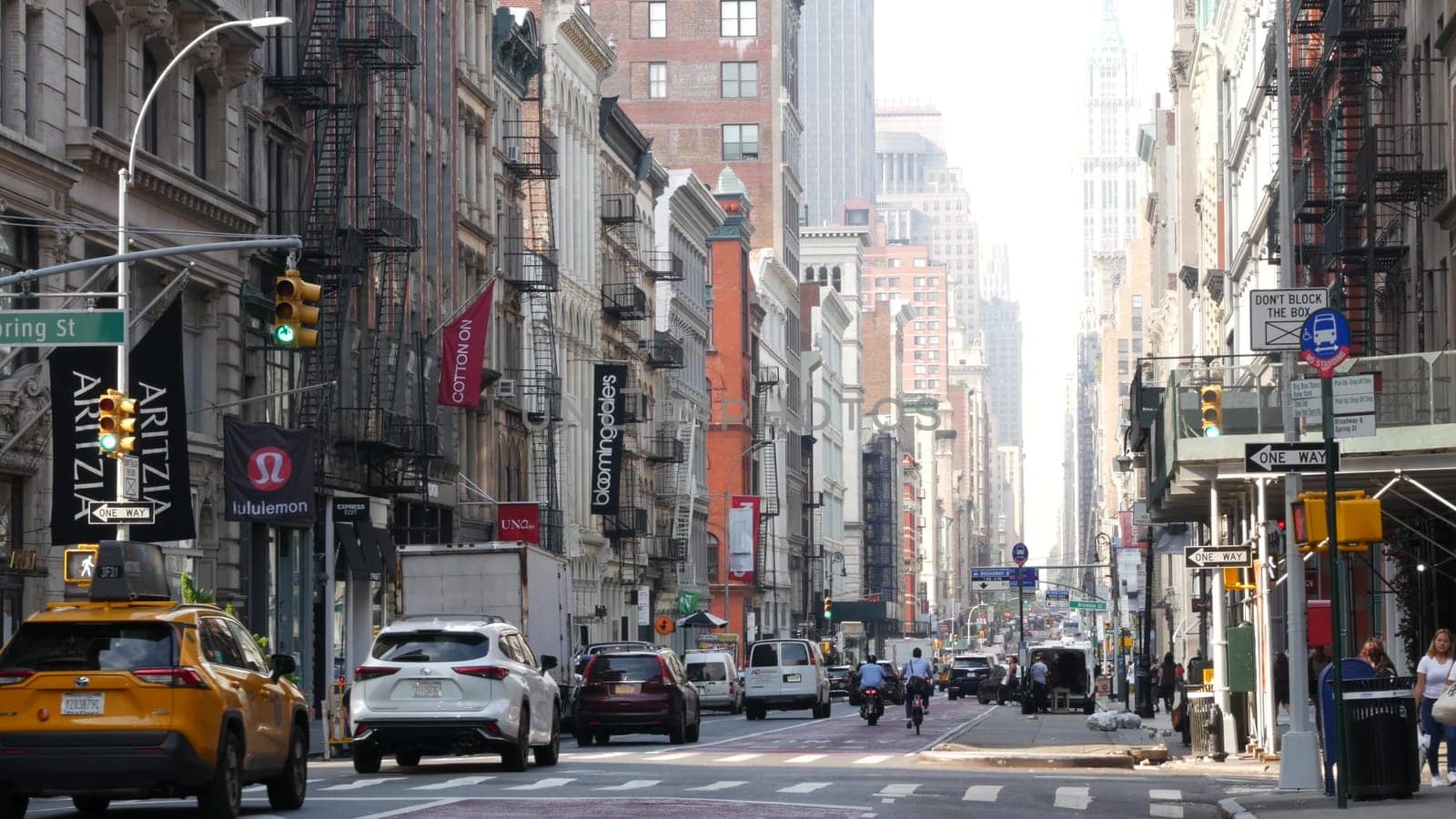 New York City, United States - 8 Sept 2023: Manhattan Soho District, Broadway street perspective. Urban road car traffic, yellow taxi, people. USA building architecture, Fashion stores for shopping.