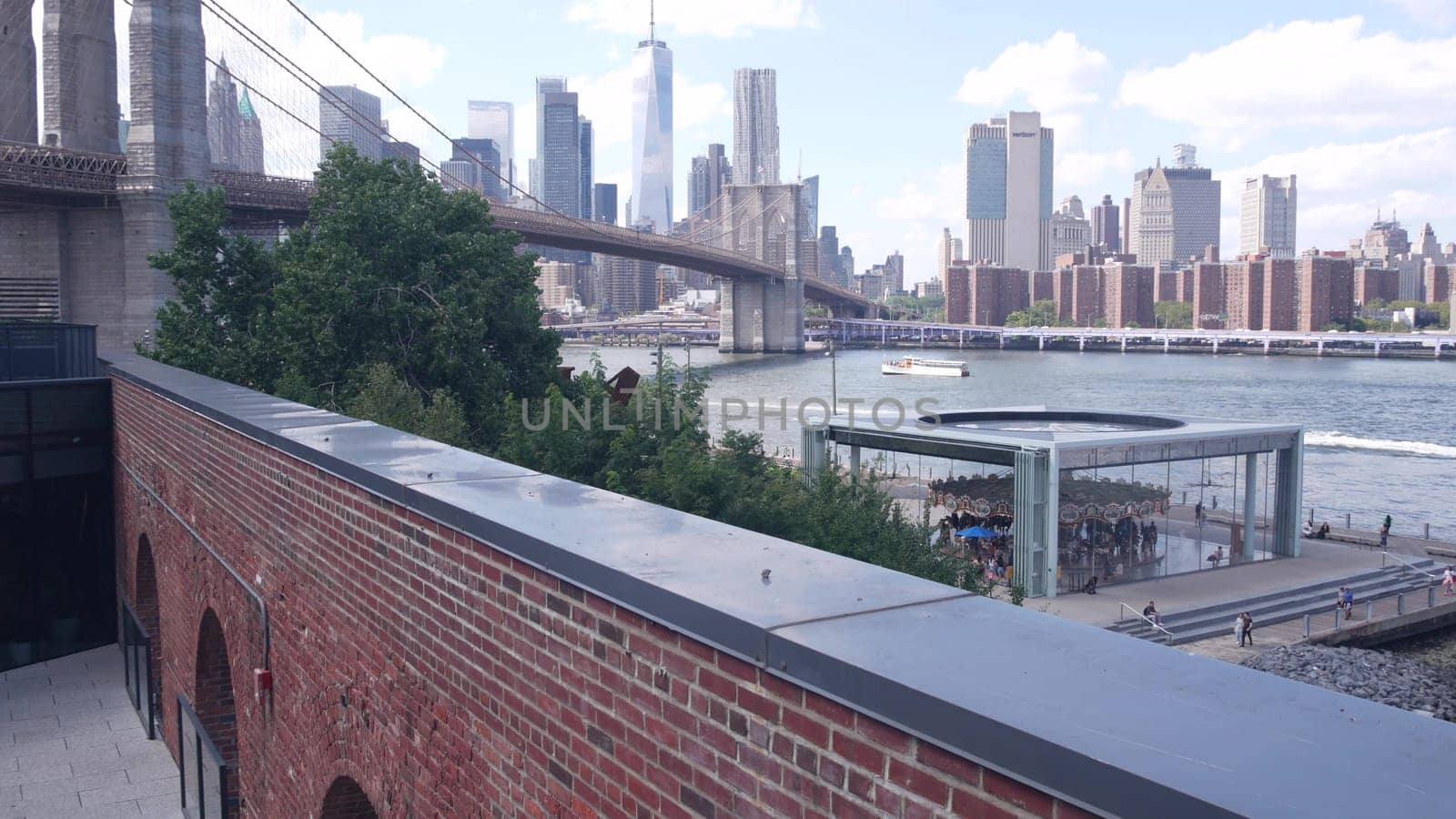 New York City, United States - 30 Aug 2023: Manhattan downtown skyline, waterfront cityscape from Time Out Market. Riverfront Carousel in Dumbo near Brooklyn Bridge. World Trade Center skyscraper.