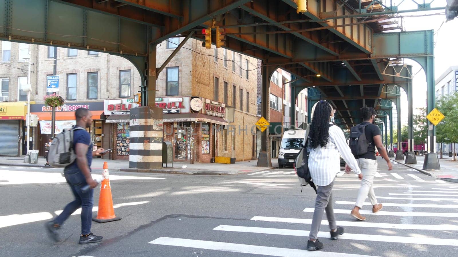 New York City, United States - 31 Aug 2023 Elevated subway above street. Metropolitan bridge over road, Queens. Long Island metro line, Court Square. Cars under metallic railway track. People on zebra