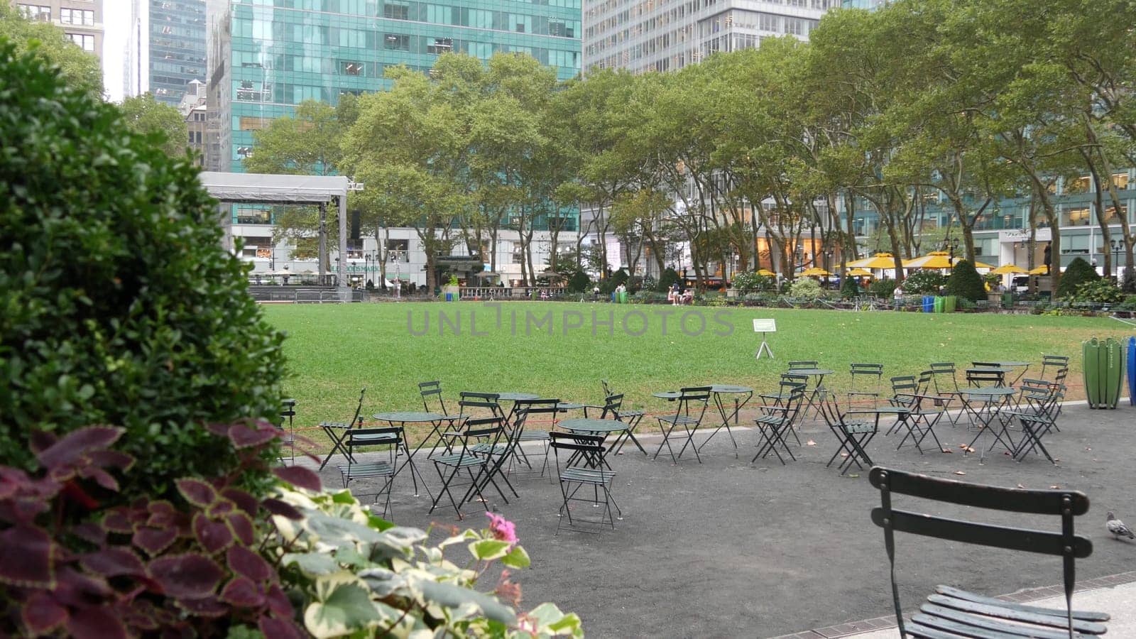 New York City, United States - 13 Sept 2023: Manhattan Midtown Bryant Park with Public library, 42 street and Fifth 5 avenue. USA landmark. Empty chair and table in summer greenery. Green grass lawn.