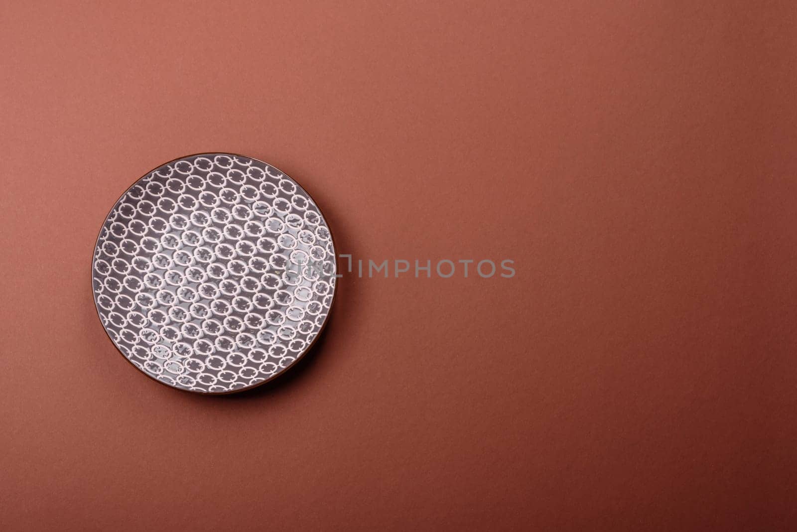 Empty ceramic plate on a monochrome brown background. Empty plate with cutlery on a dining table