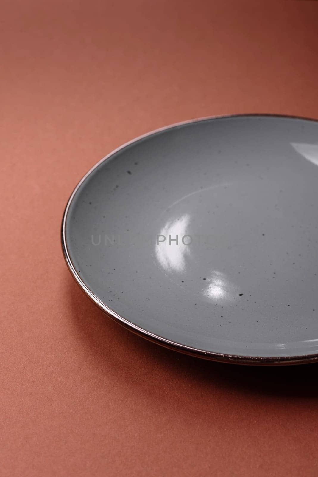 Empty ceramic plate on a monochrome brown background. Empty plate with cutlery on a dining table