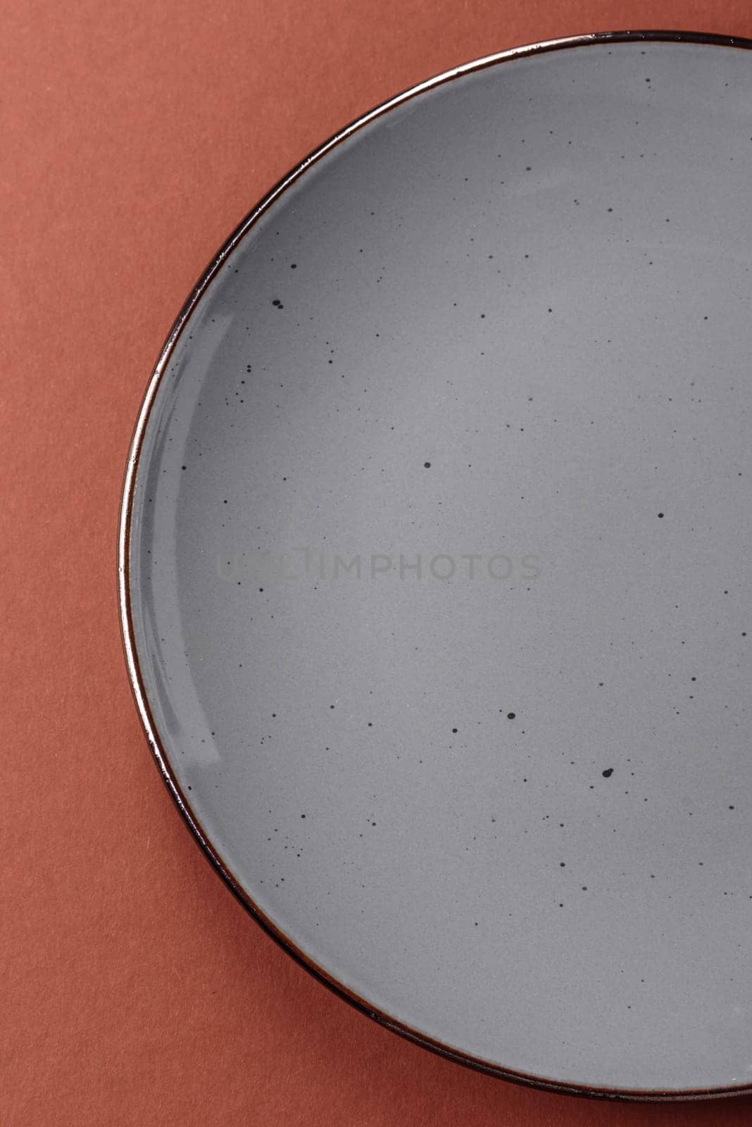 Empty ceramic plate on a monochrome brown background. Empty plate with cutlery on a dining table