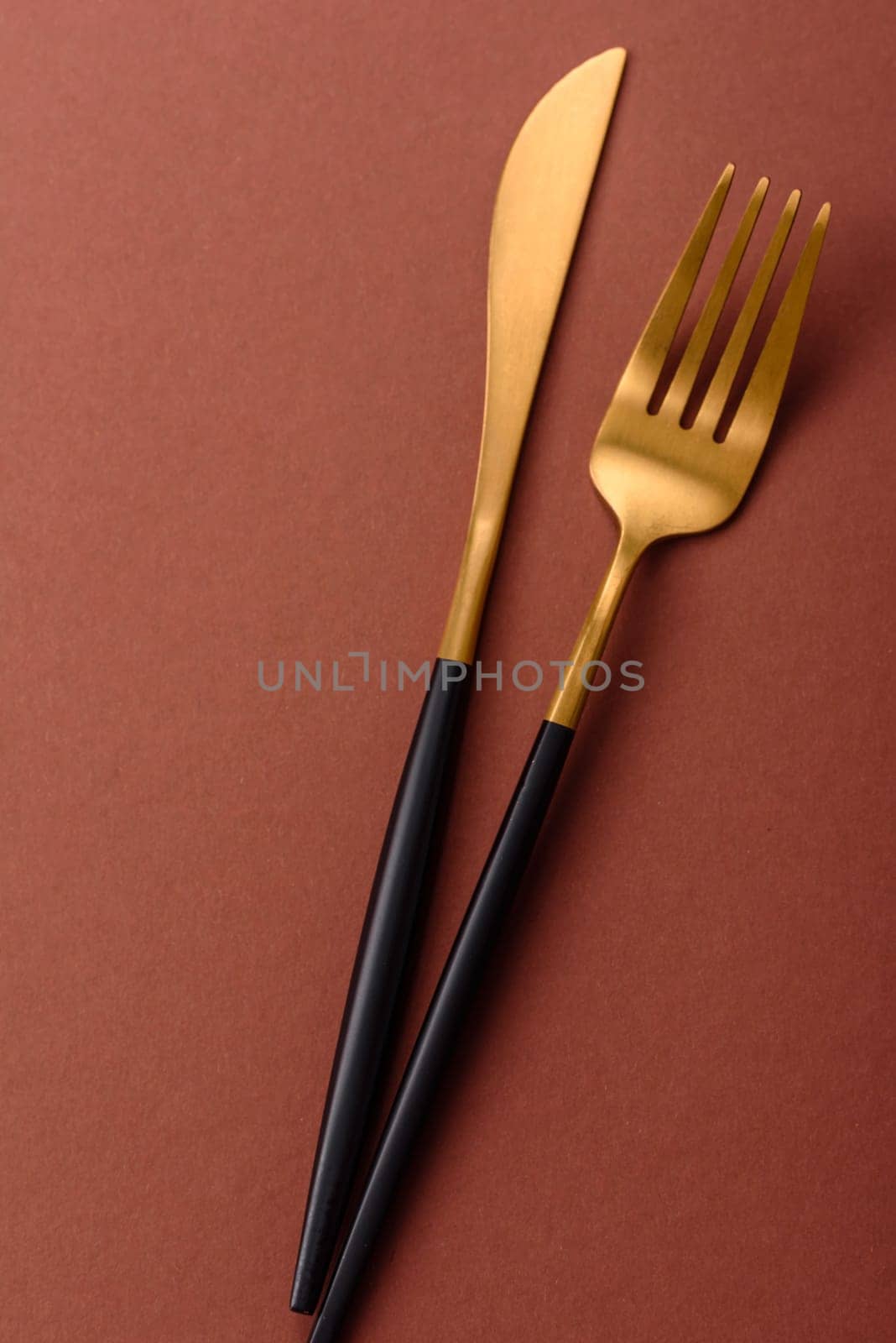 Knife and fork, cutlery on a brown dining table. Utensils and crockery for preparing dinner