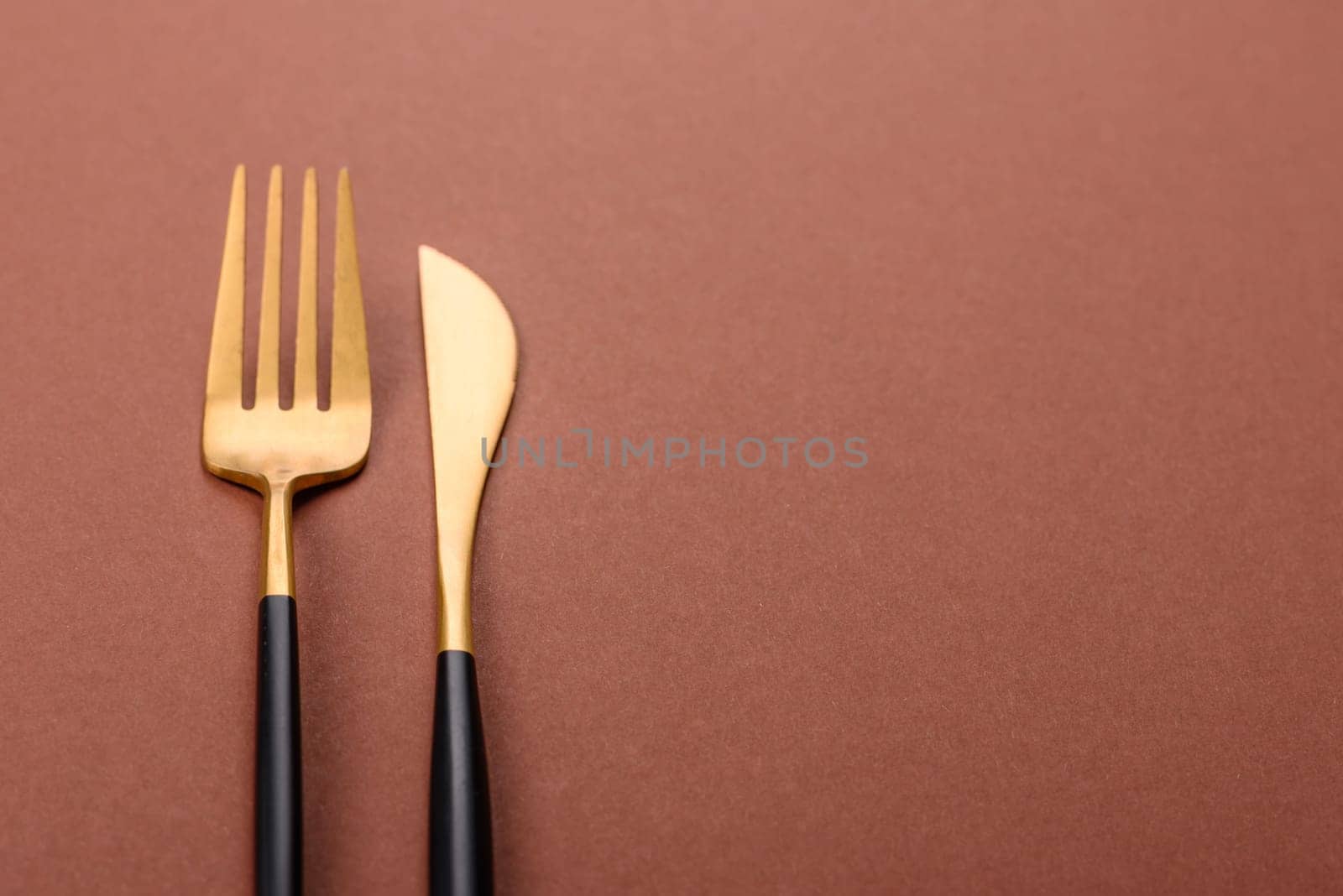 Knife and fork, cutlery on a brown dining table. Utensils and crockery for preparing dinner