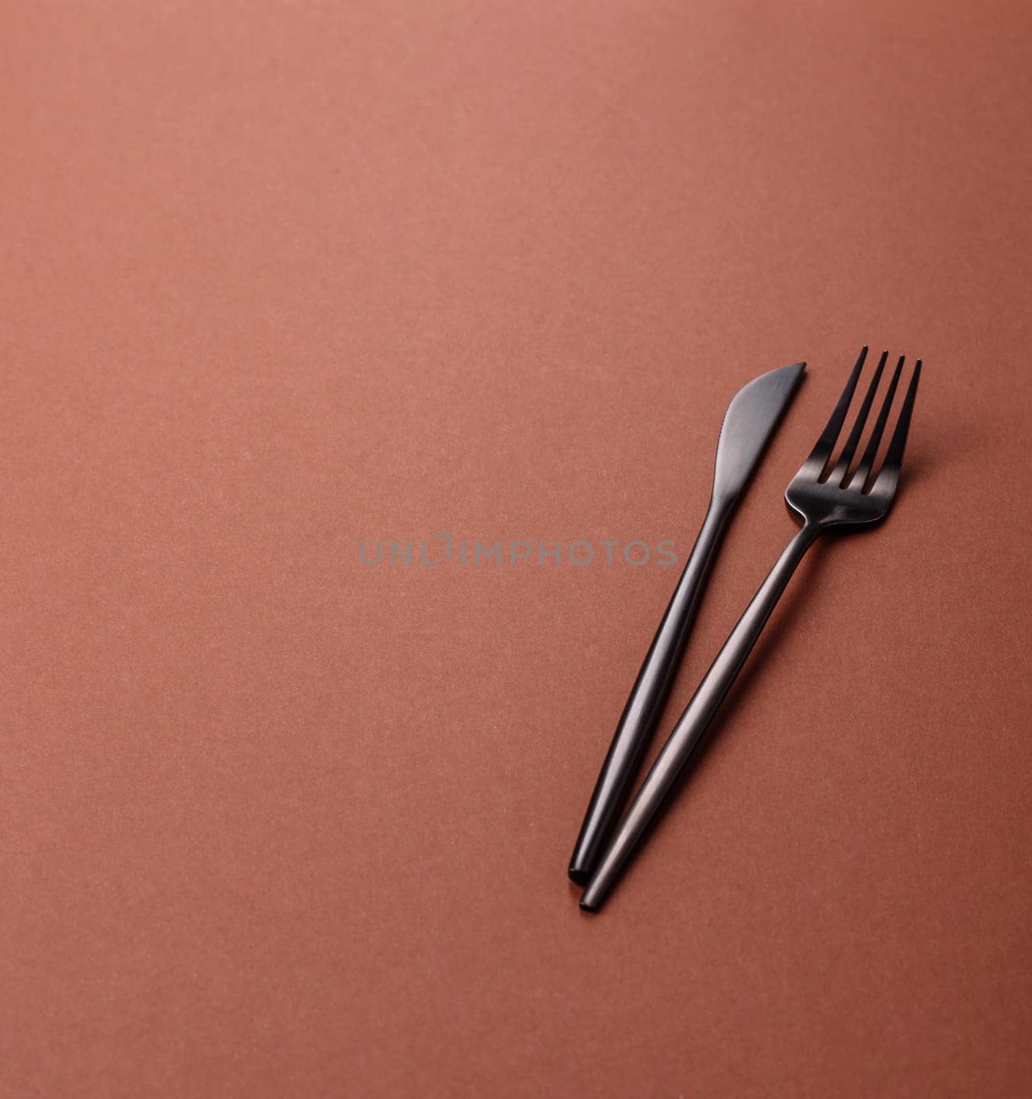 Knife and fork, cutlery on a brown dining table. Utensils and crockery for preparing dinner
