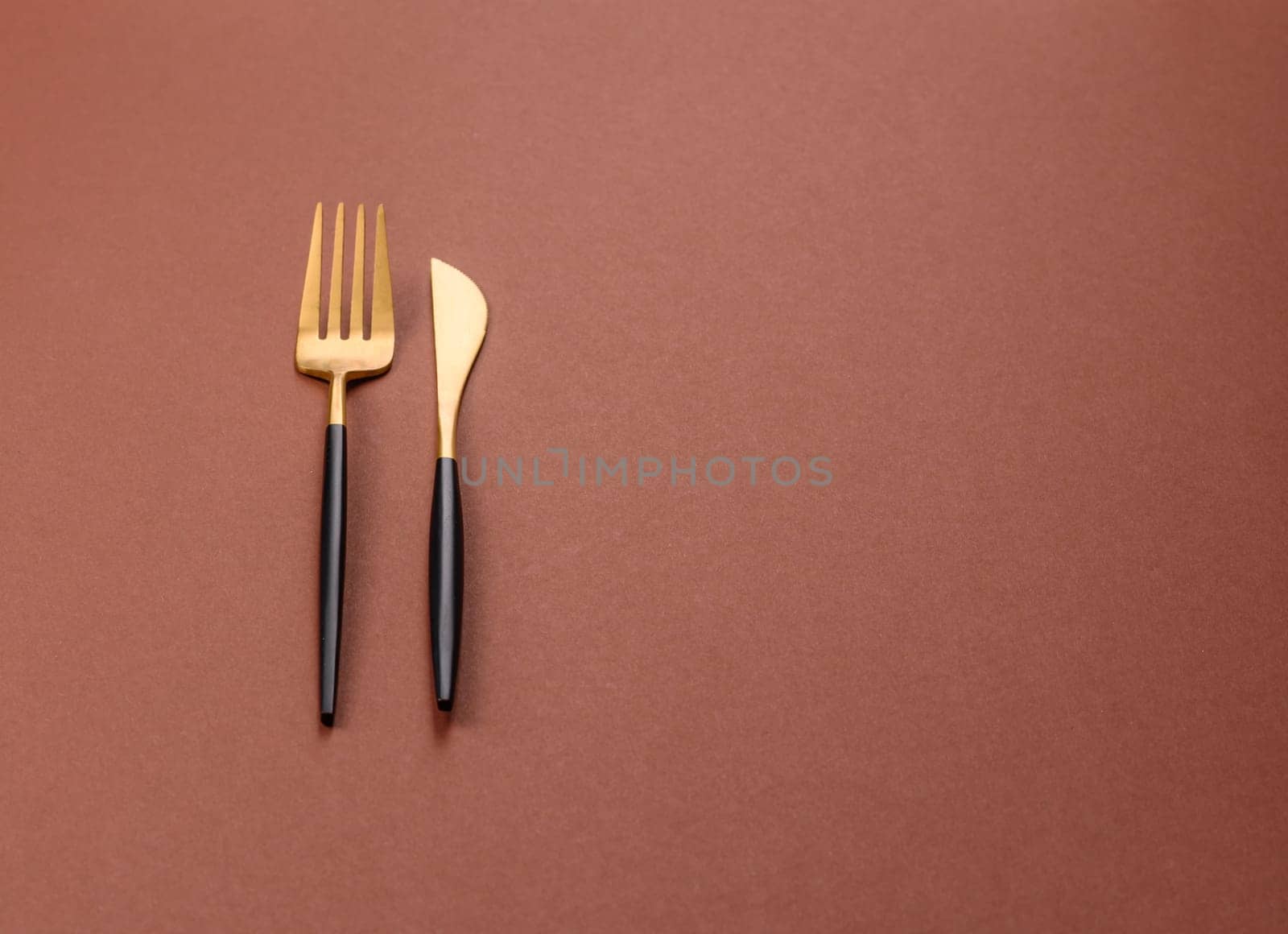 Knife and fork, cutlery on a brown dining table. Utensils and crockery for preparing dinner