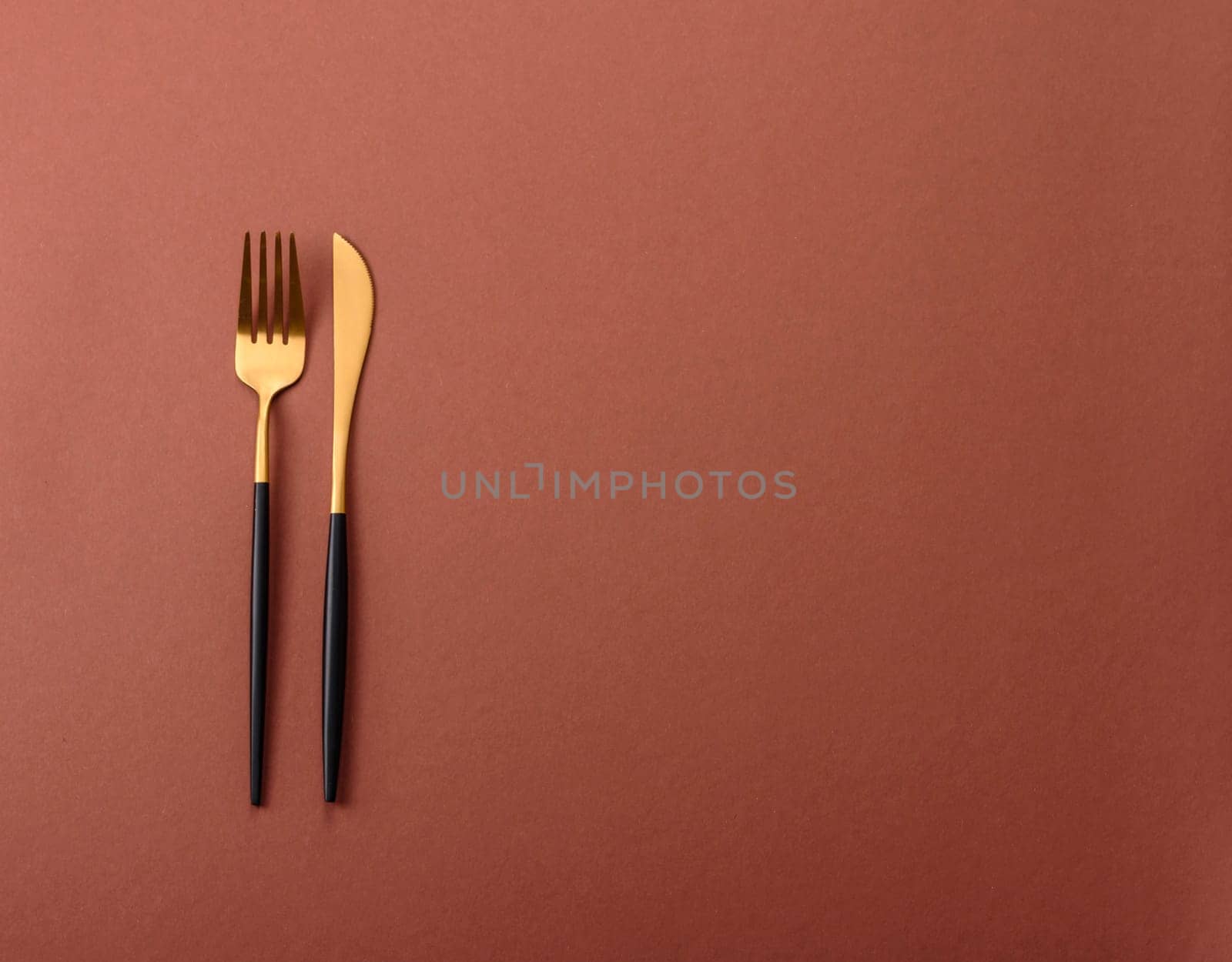 Knife and fork, cutlery on a brown dining table. Utensils and crockery for preparing dinner