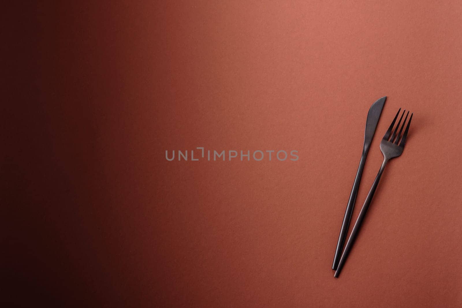 Knife and fork, cutlery on a brown dining table. Utensils and crockery for preparing dinner