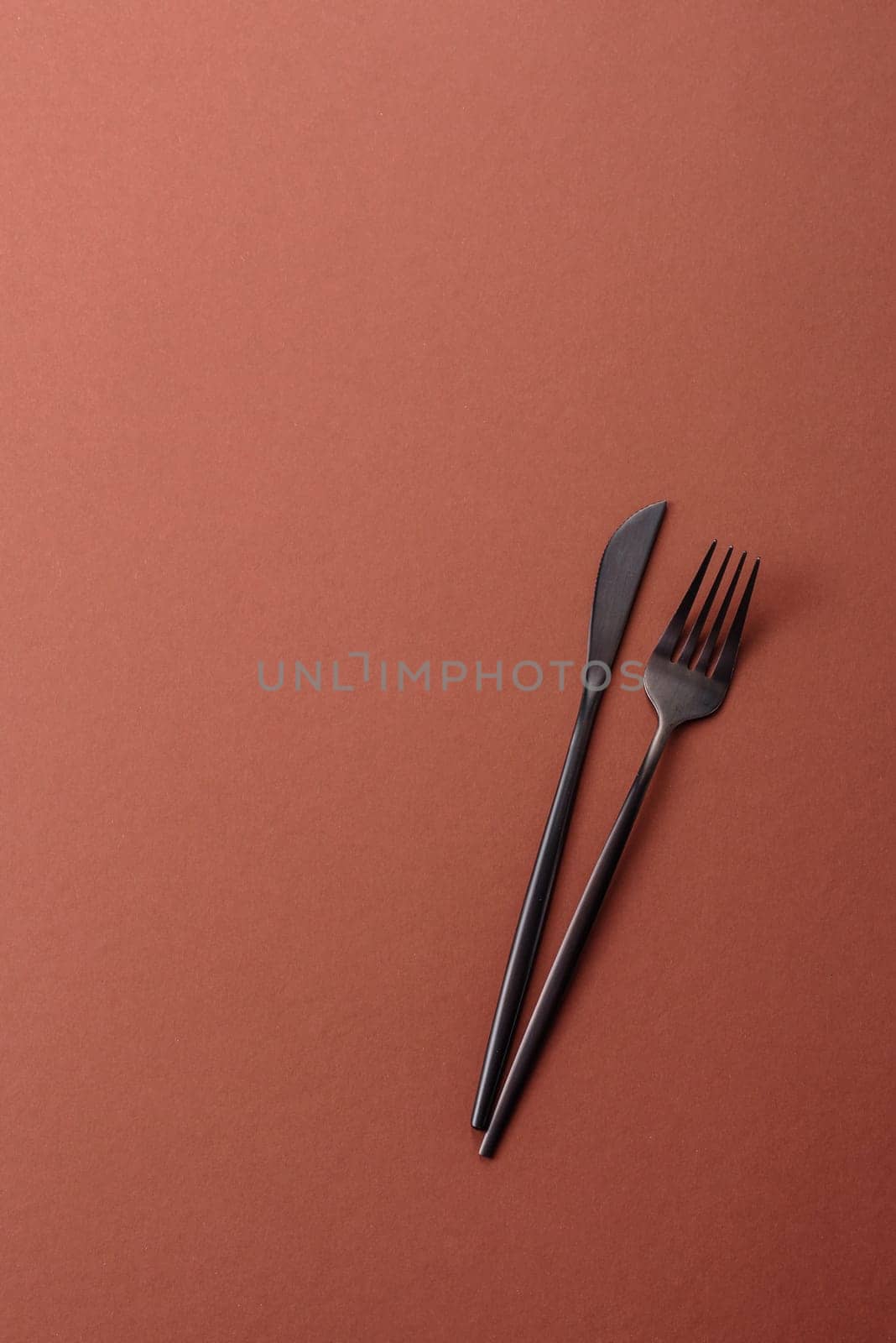 Knife and fork, cutlery on a brown dining table. Utensils and crockery for preparing dinner
