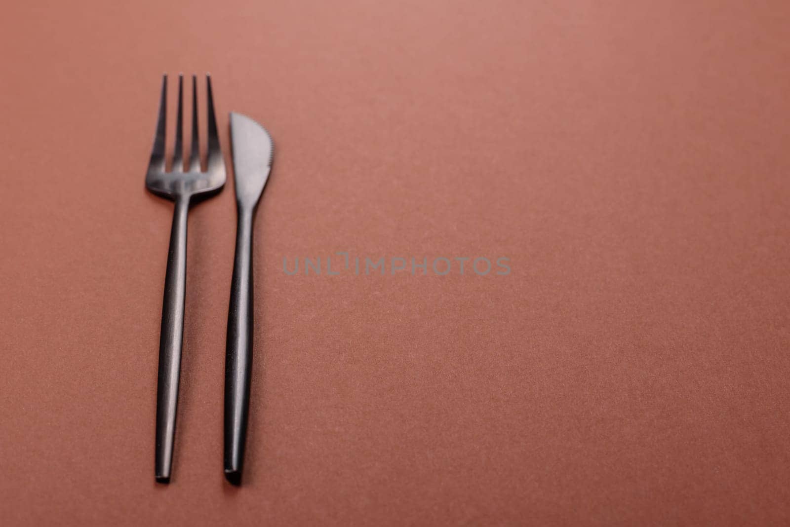 Knife and fork, cutlery on a brown dining table. Utensils and crockery for preparing dinner