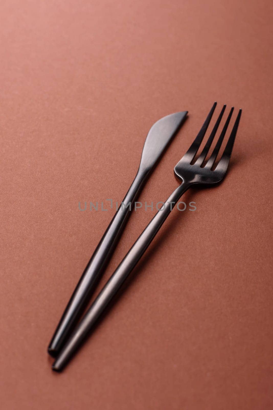 Knife and fork, cutlery on a brown dining table. Utensils and crockery for preparing dinner