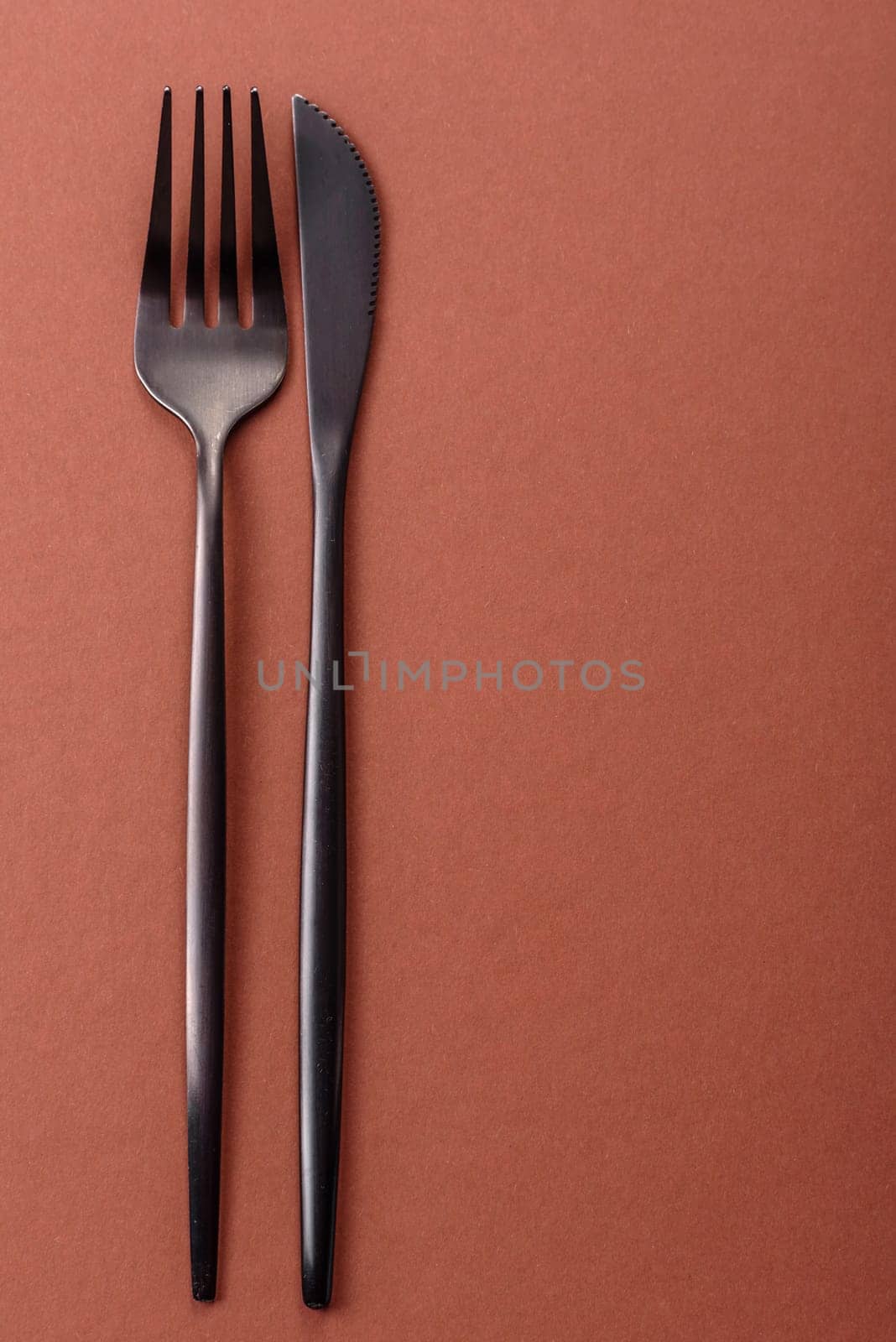 Knife and fork, cutlery on a brown dining table. Utensils and crockery for preparing dinner