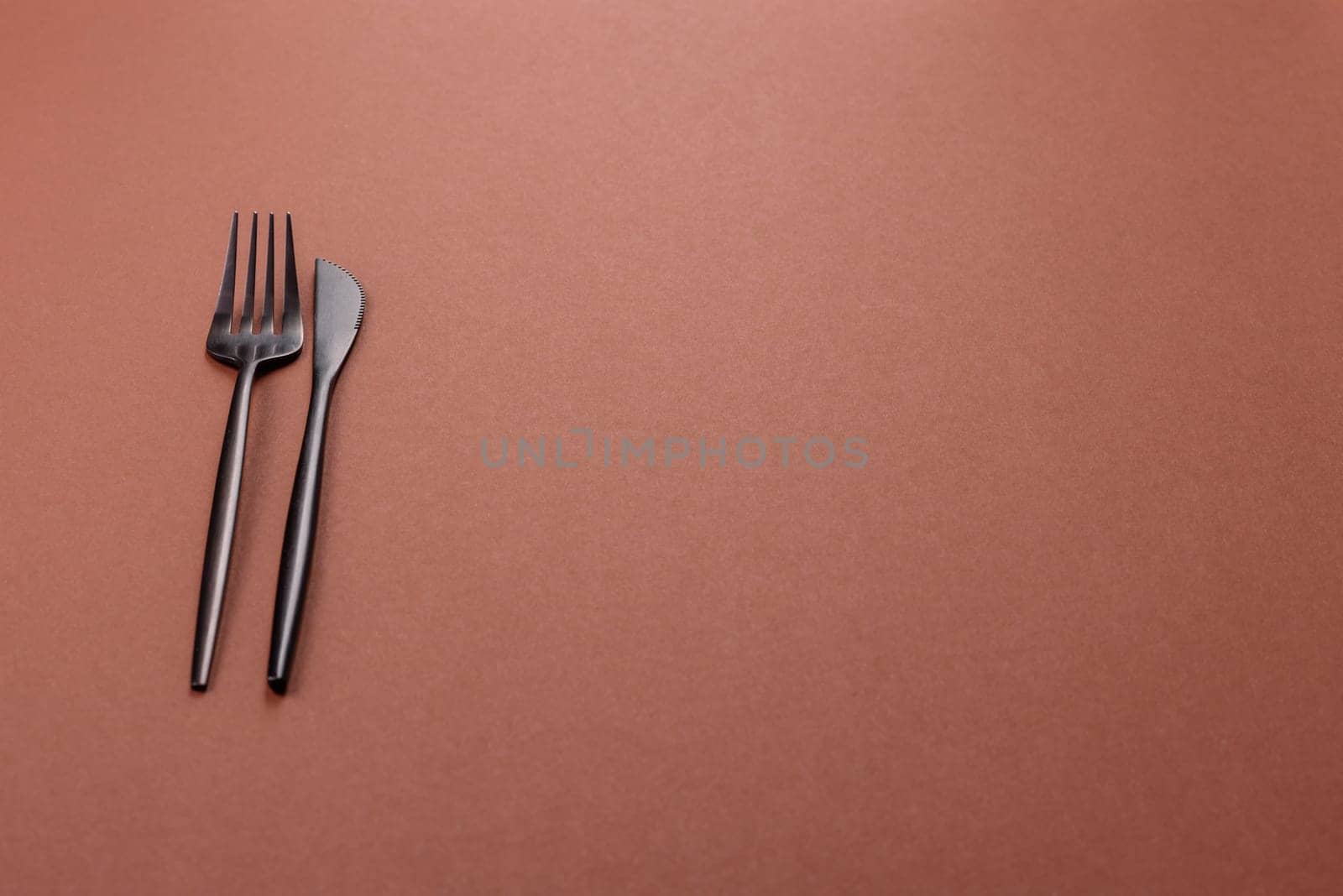 Knife and fork, cutlery on a brown dining table. Utensils and crockery for preparing dinner