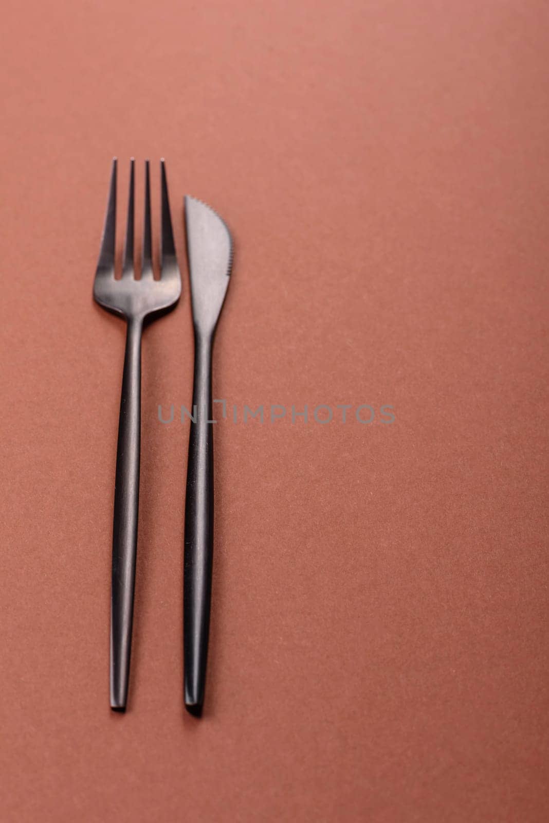 Knife and fork, cutlery on a brown dining table. Utensils and crockery for preparing dinner