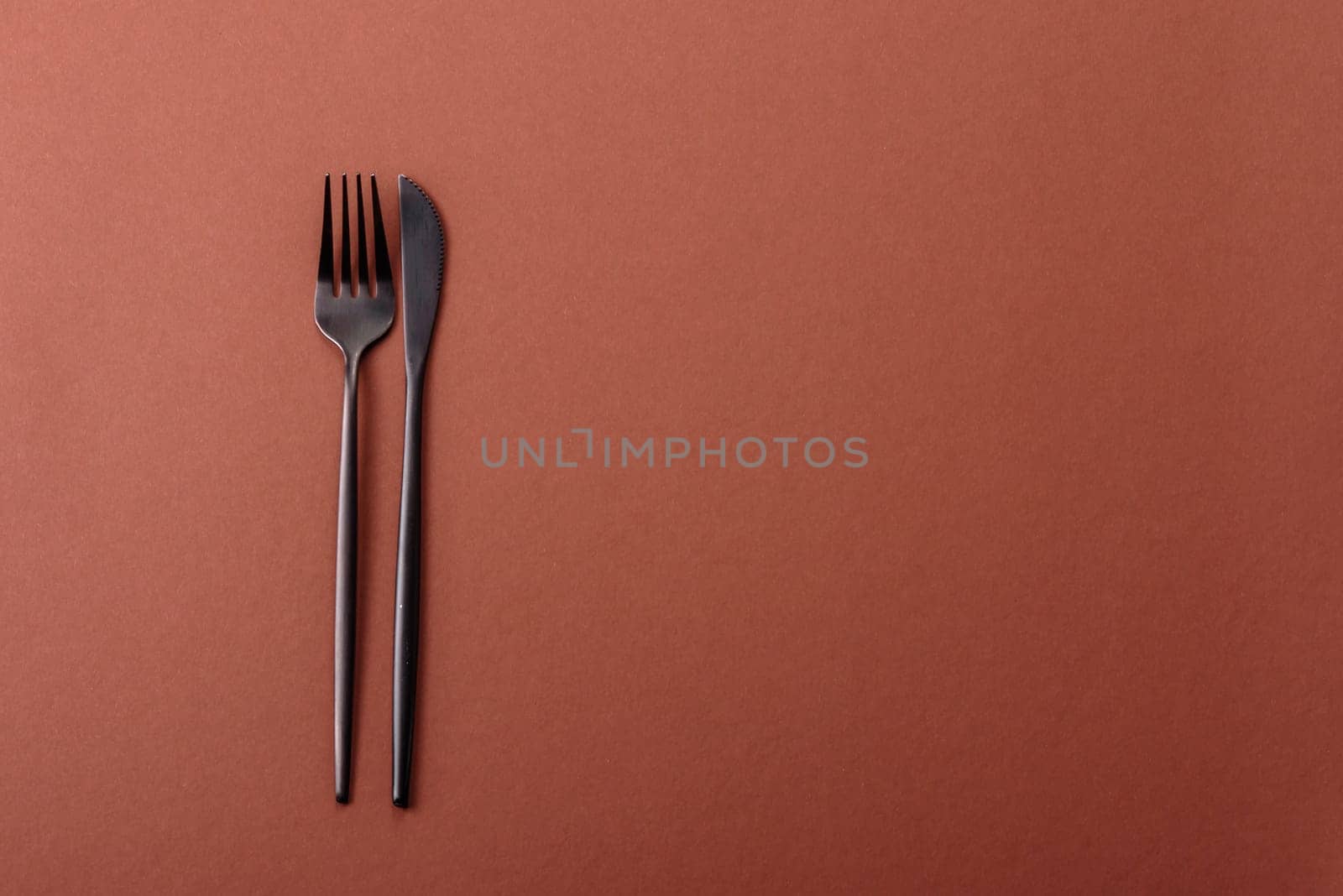 Knife and fork, cutlery on a brown dining table. Utensils and crockery for preparing dinner