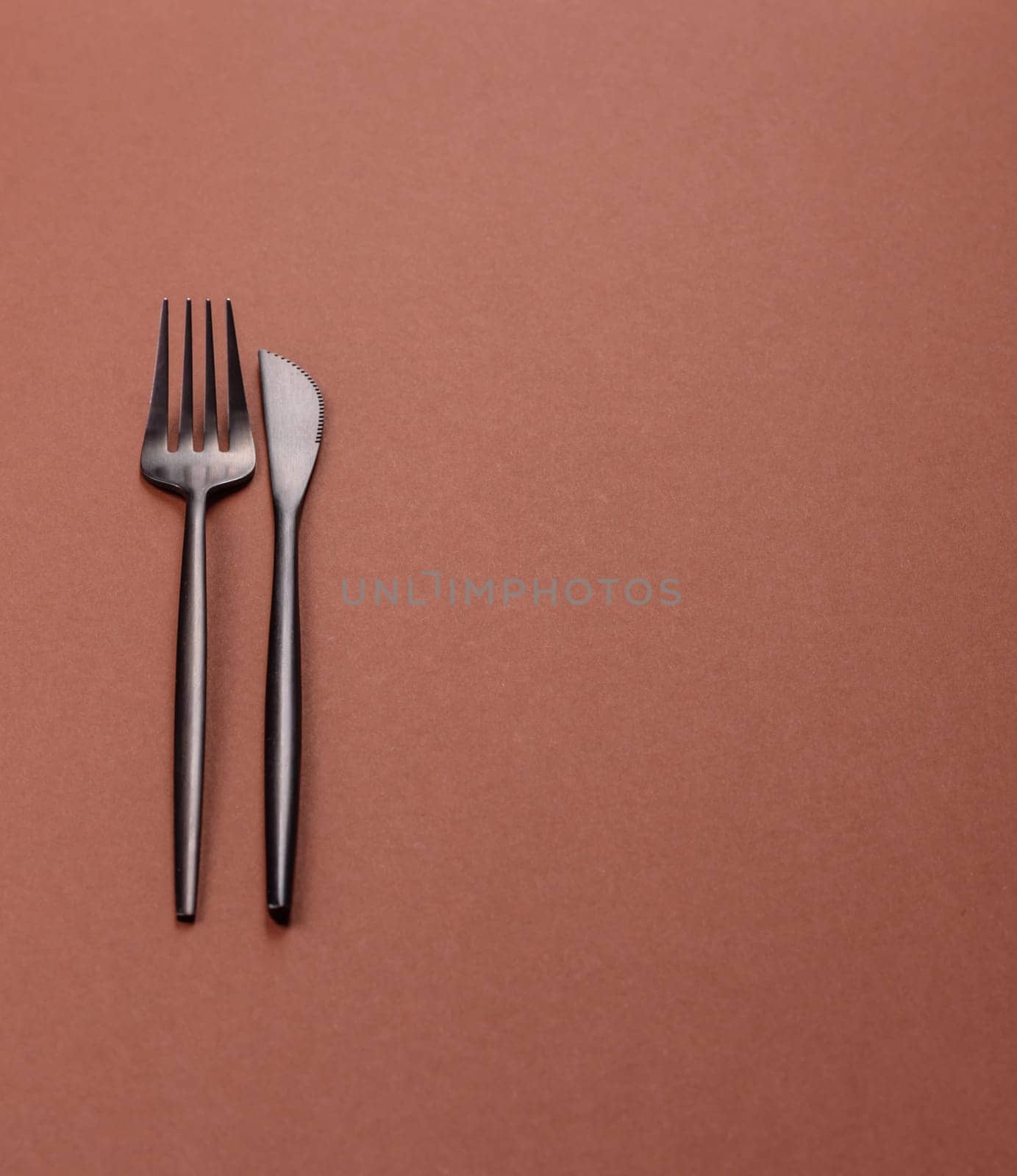 Knife and fork, cutlery on a brown dining table. Utensils and crockery for preparing dinner