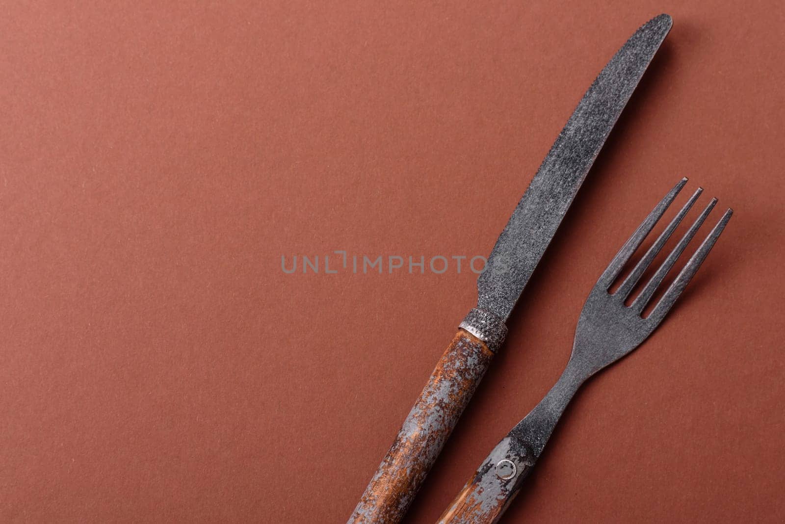 Knife and fork, cutlery on a brown dining table. Utensils and crockery for preparing dinner