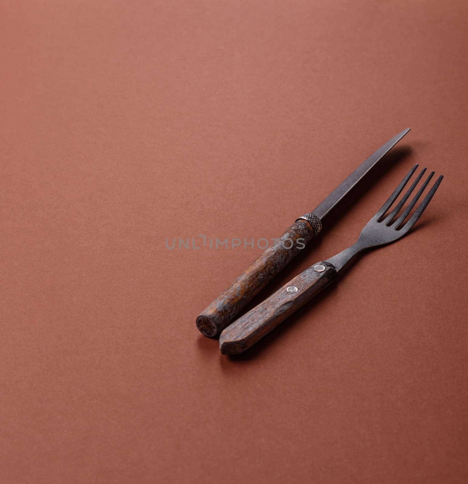 Knife and fork, cutlery on a brown dining table. Utensils and crockery for preparing dinner